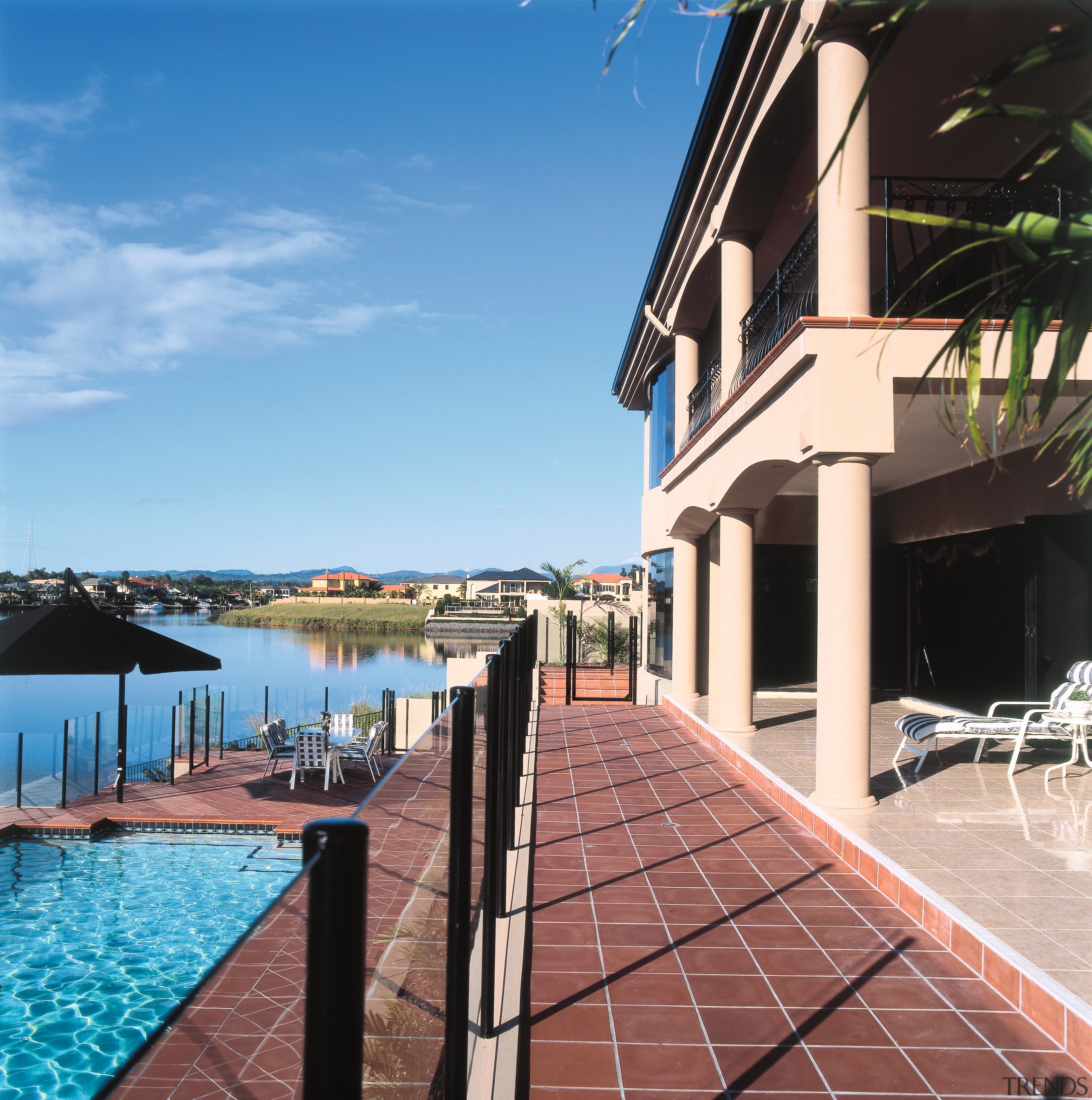 A view of a swimming pool area, red apartment, building, condominium, estate, home, house, leisure, outdoor structure, property, real estate, resort, roof, sea, sky, swimming pool, vacation, villa, water, teal