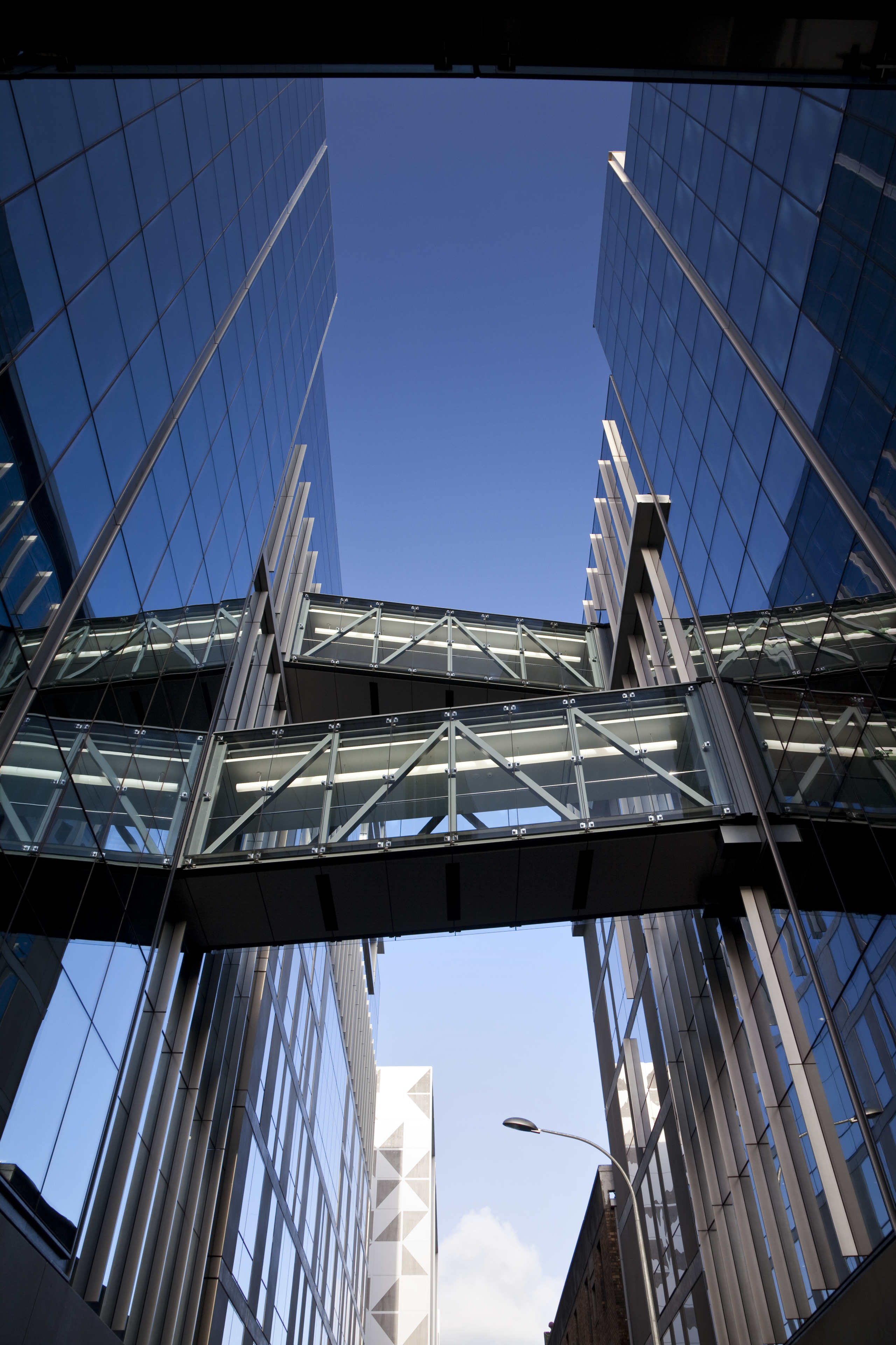 Low angle view of skybridges at the Britomart architecture, building, daylighting, daytime, facade, fixed link, landmark, line, metropolis, metropolitan area, reflection, sky, skyscraper, structure, symmetry, tower block, urban area, blue, black