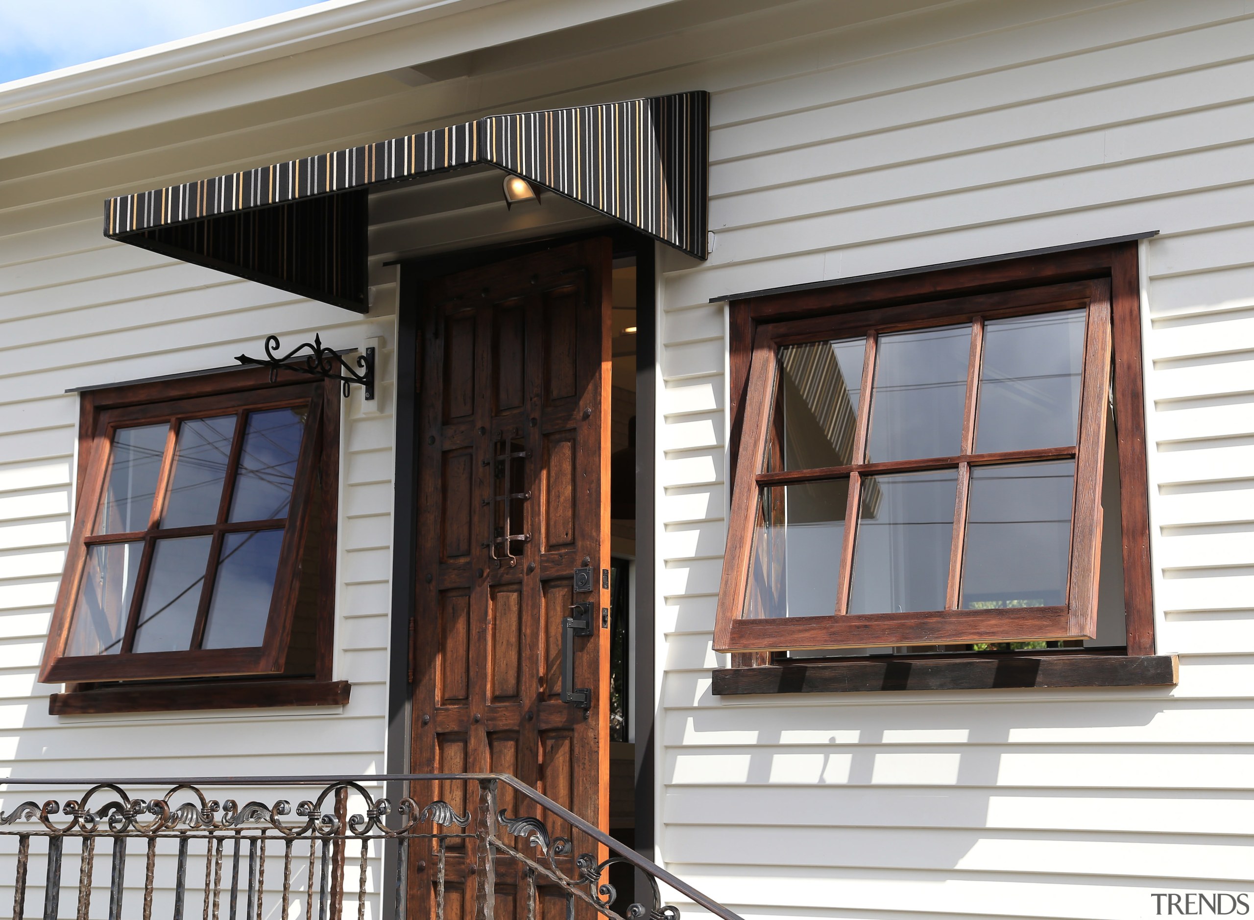 An old-world front door and wrought iron railing door, facade, home, house, siding, window, gray, black