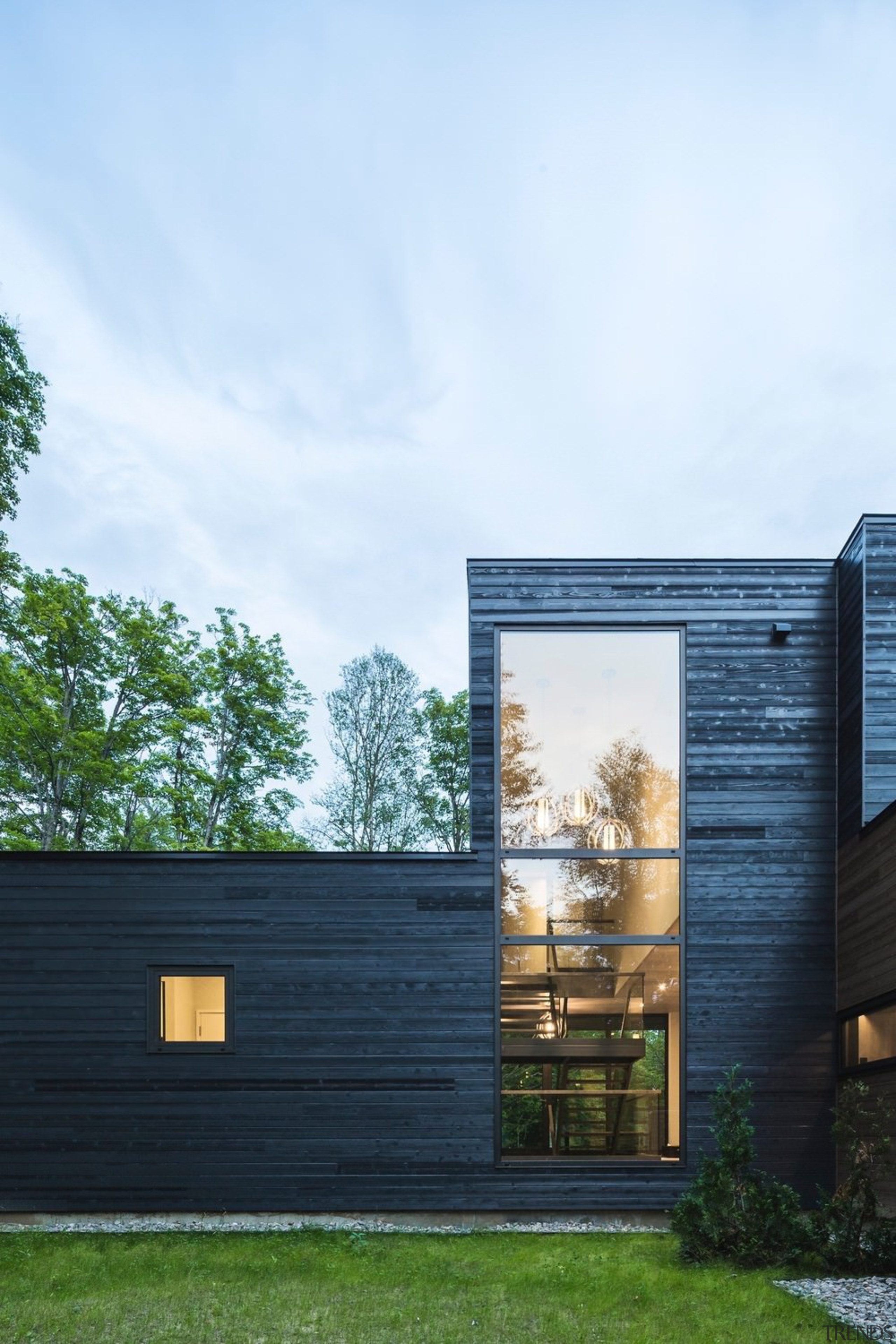 A giant window reveals the home's feature staircase architecture, building, cottage, facade, home, house, real estate, residential area, shed, siding, sky, wood, white