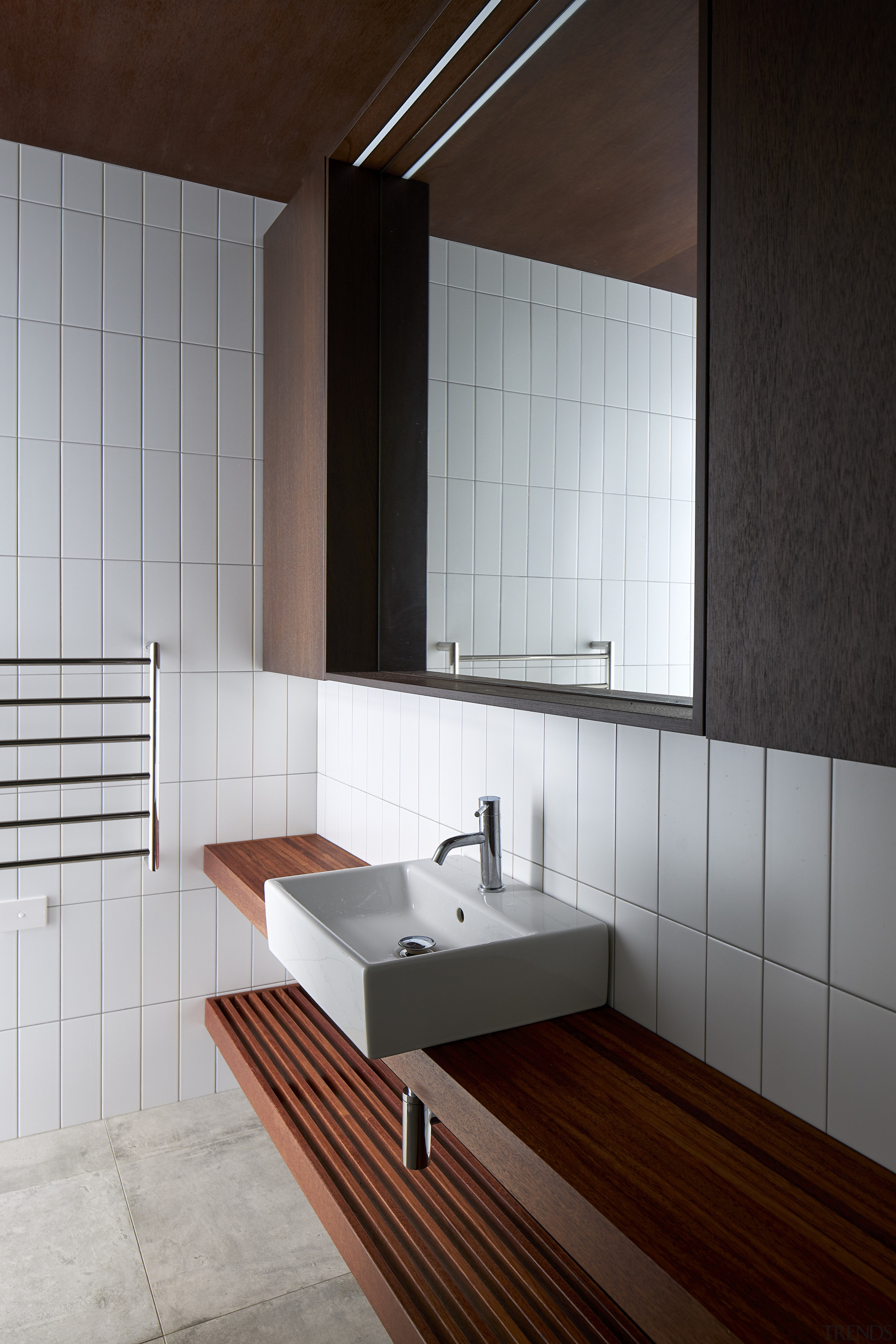 The bathroom continues the dark-toned joinery look seen 