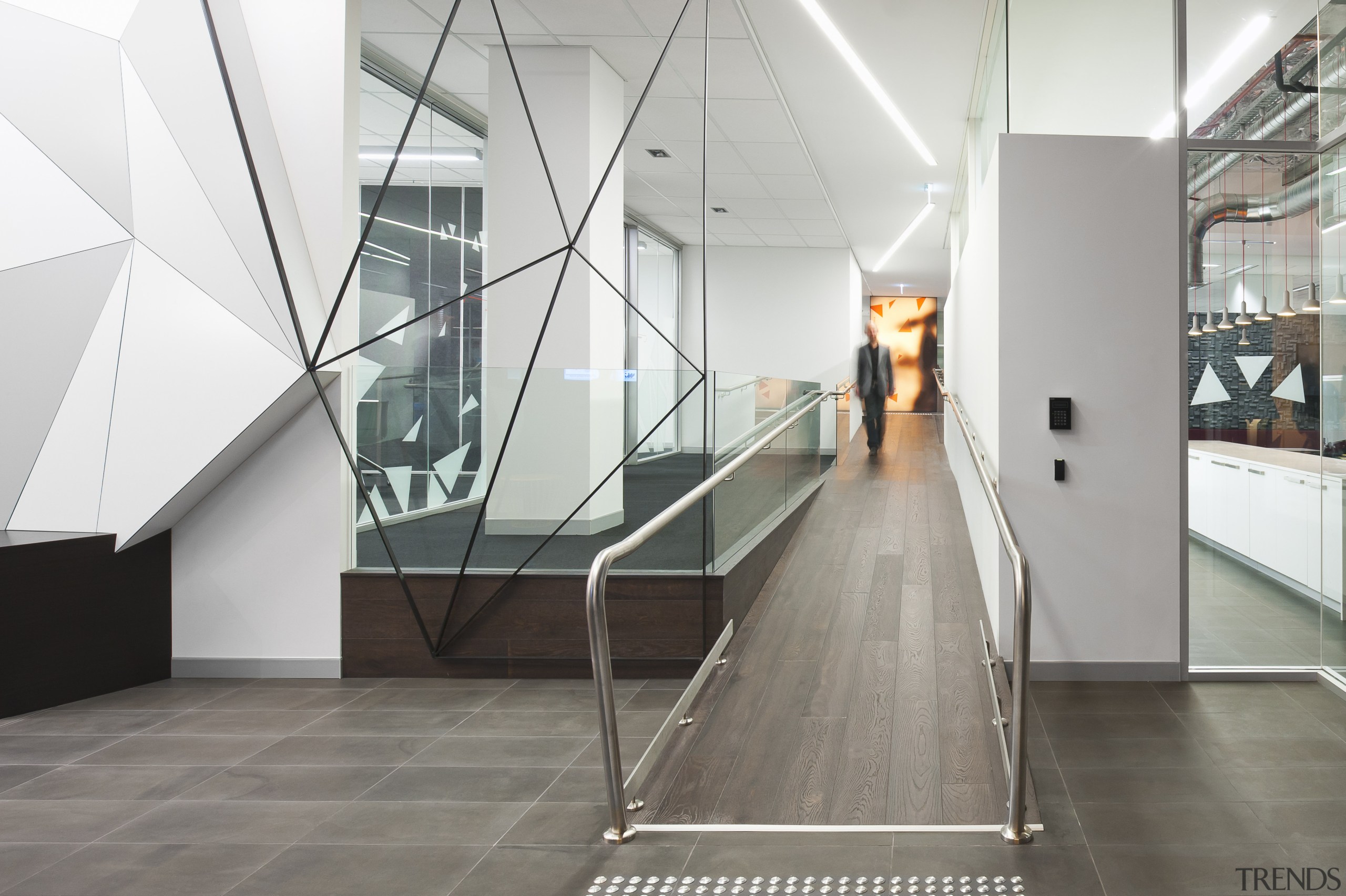 A multifaceted facade behind the reception desk of architecture, daylighting, floor, flooring, glass, handrail, interior design, product design, stairs, tourist attraction, white, gray