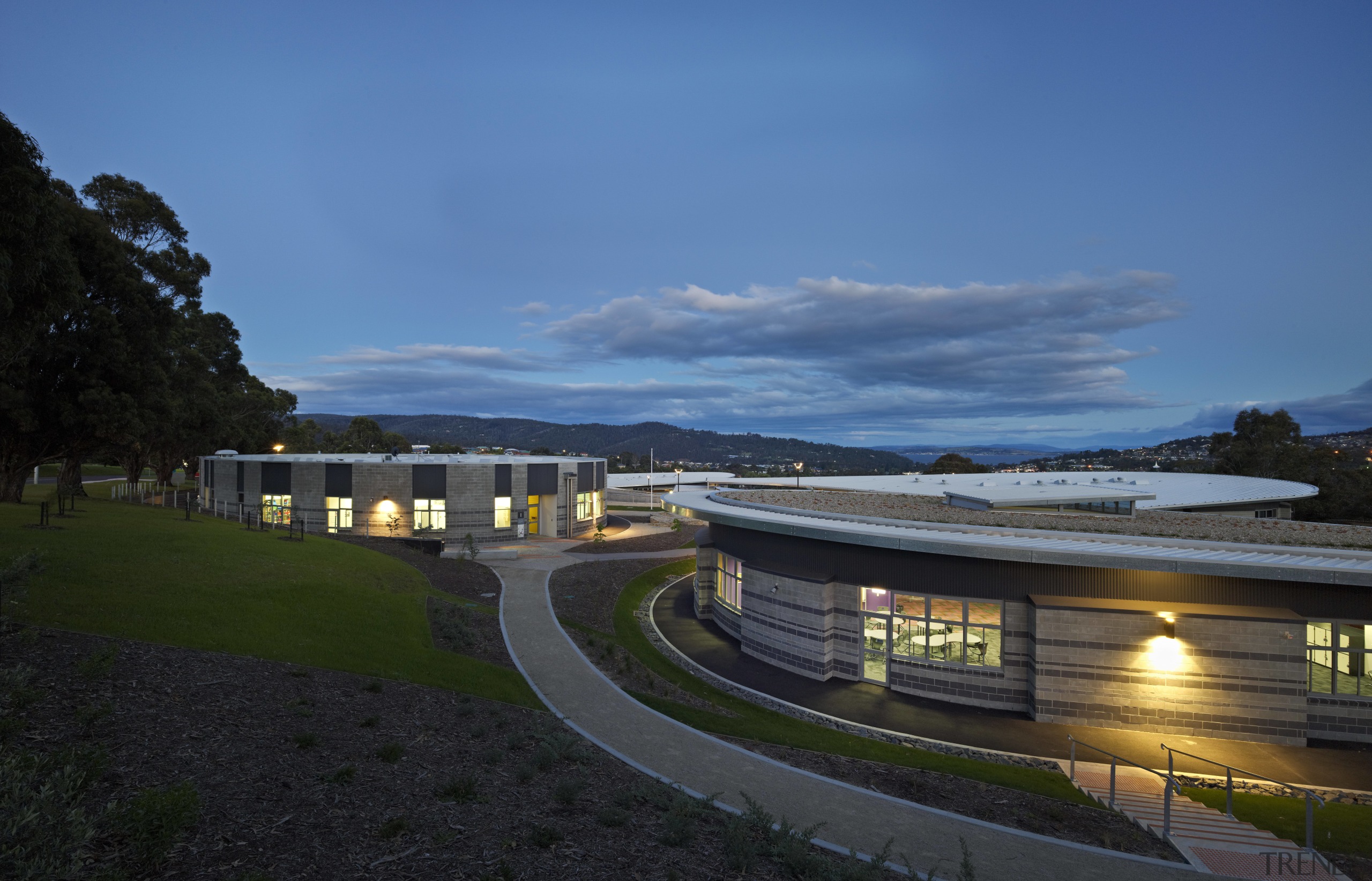 View of exterior of school building at dusk. architecture, building, city, cloud, corporate headquarters, estate, evening, home, house, landscape, property, real estate, residential area, roof, sky, suburb, black, teal