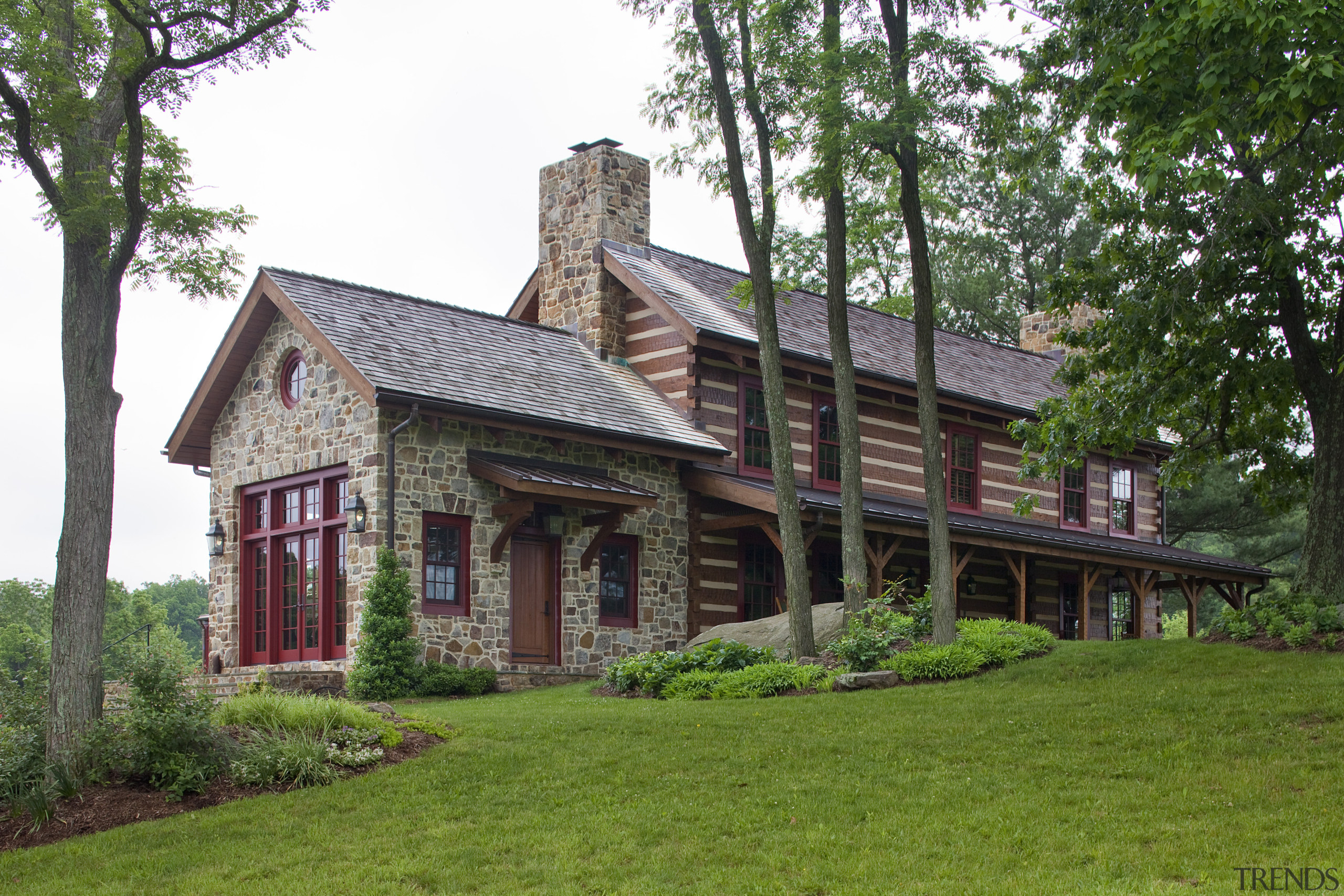 View of home with red window frames. - cottage, estate, farmhouse, grass, historic house, home, house, log cabin, manor house, mansion, plantation, property, real estate, tree, green