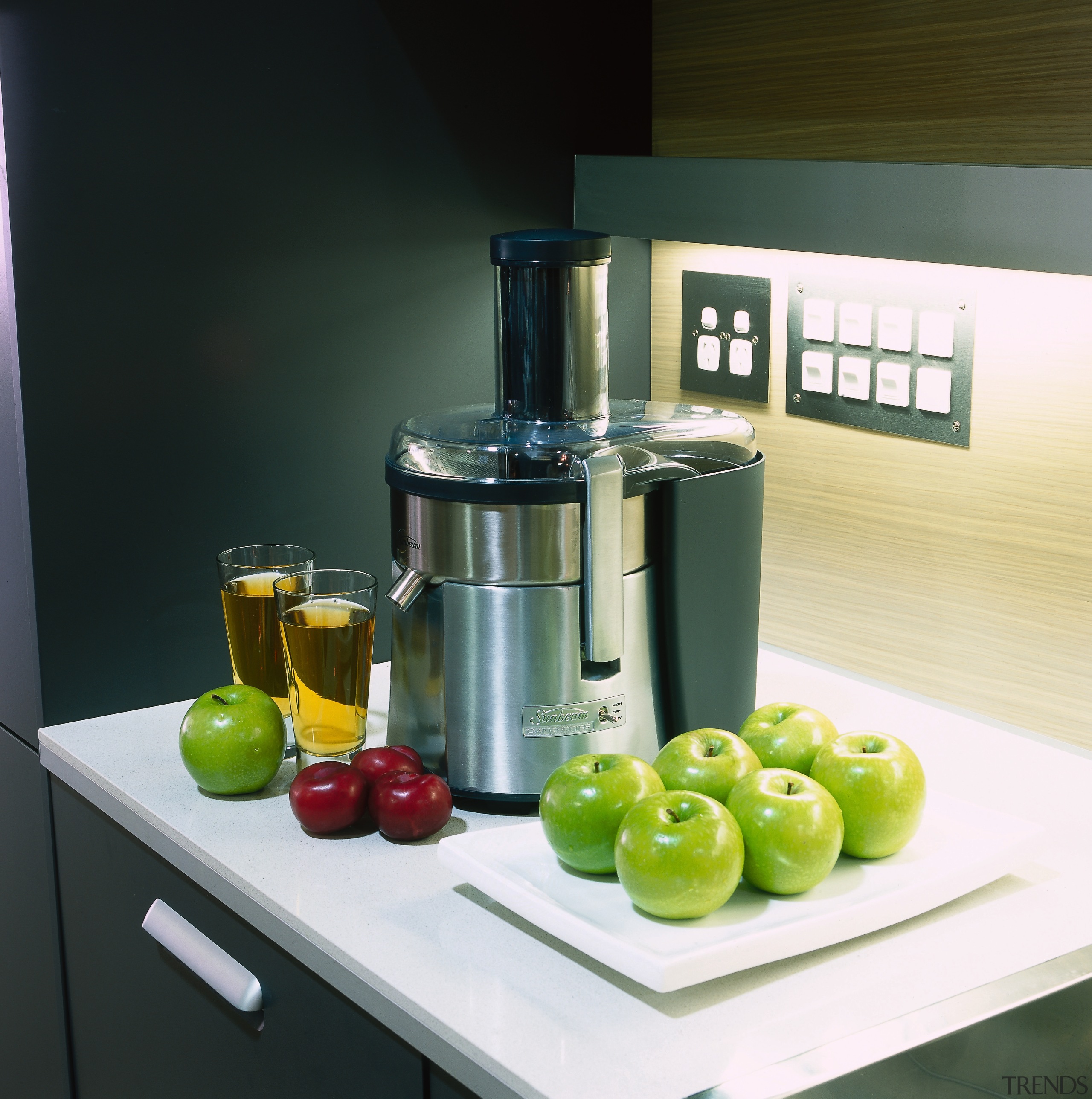 Metal juicer on benchtop surrounded by apples. - blender, food processor, juicer, kitchen appliance, product, product design, small appliance, black