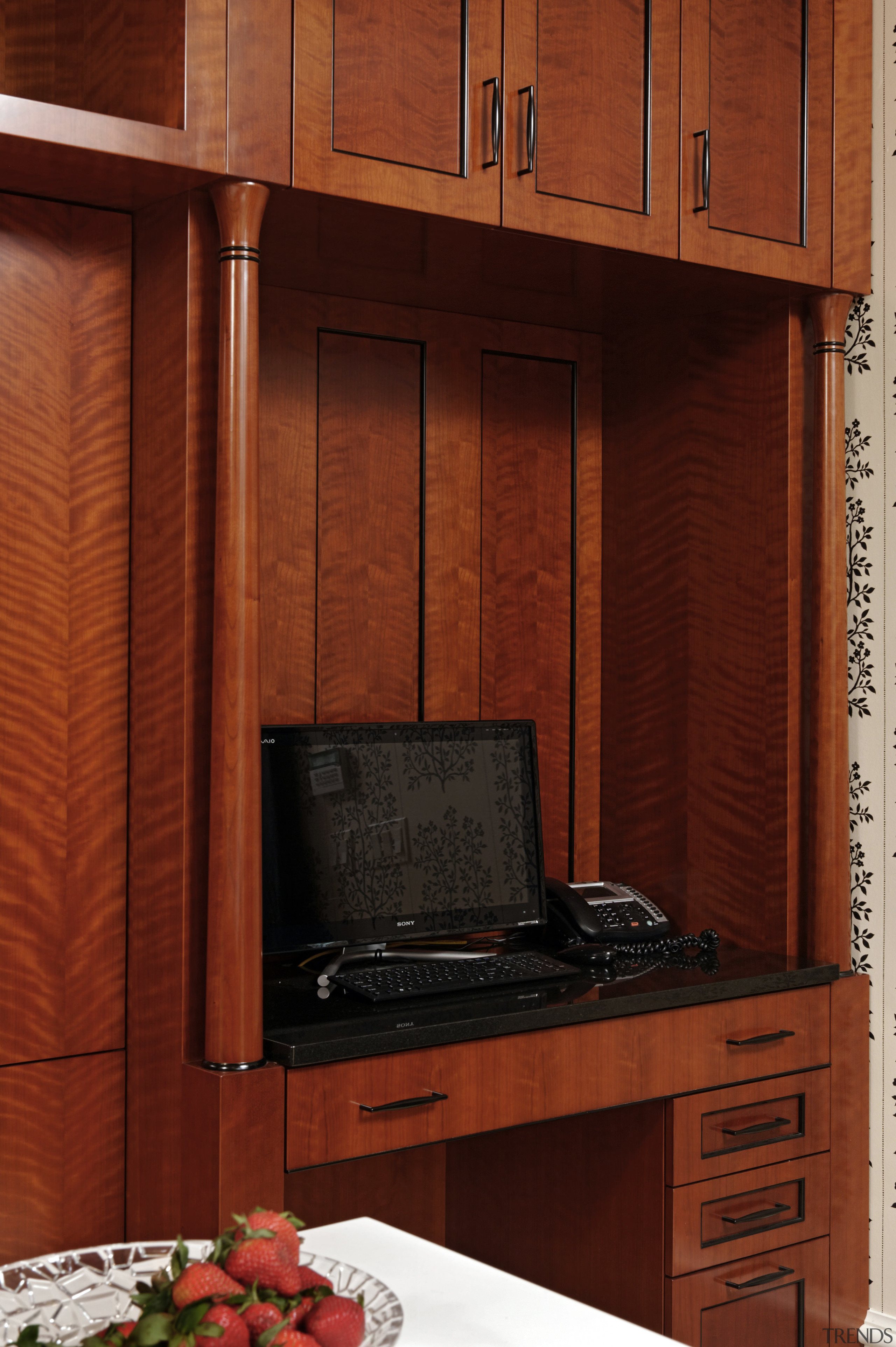 A small writing area cum home office tucked cabinetry, furniture, wall, wood, wood stain, red