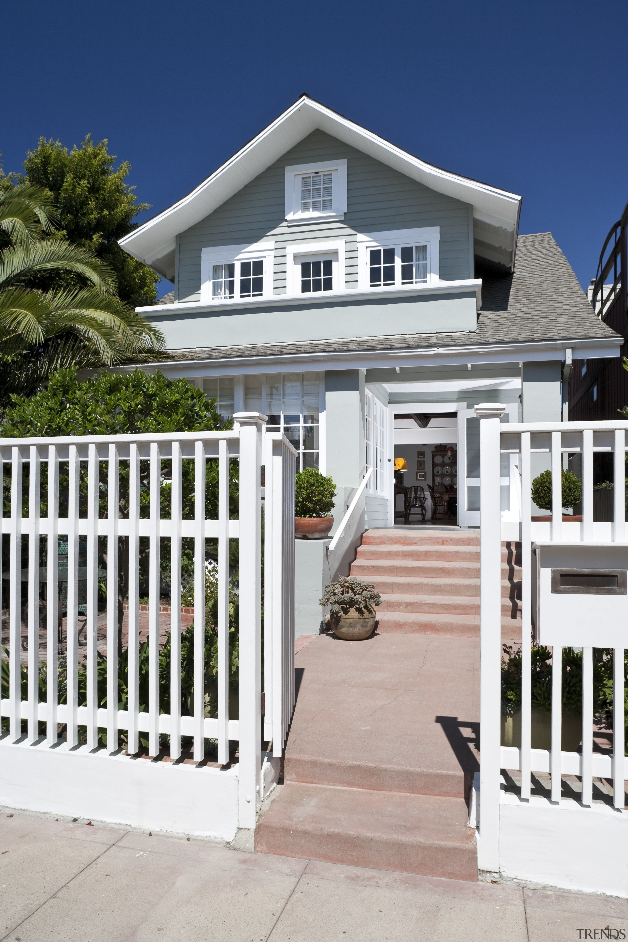 Exterior view of the entrance way to this baluster, cottage, estate, facade, fence, gate, home, house, outdoor structure, picket fence, porch, property, real estate, residential area, siding, walkway, gray, white
