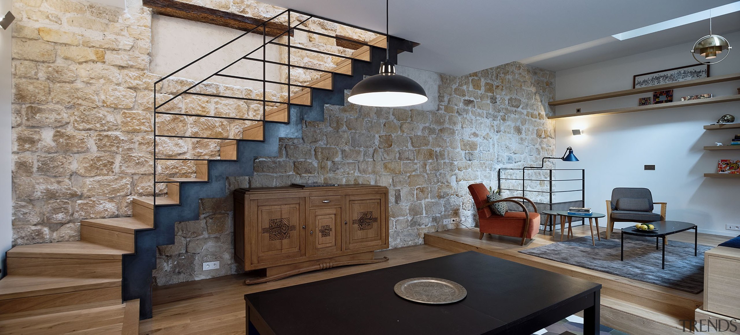 View of the living room and staircase from architecture, brick, building, ceiling, countertop, floor, flooring, furniture, hardwood, home, house, interior design, living room, loft, property, real estate, room, stairs, stone wall, table, wall, wood, gray