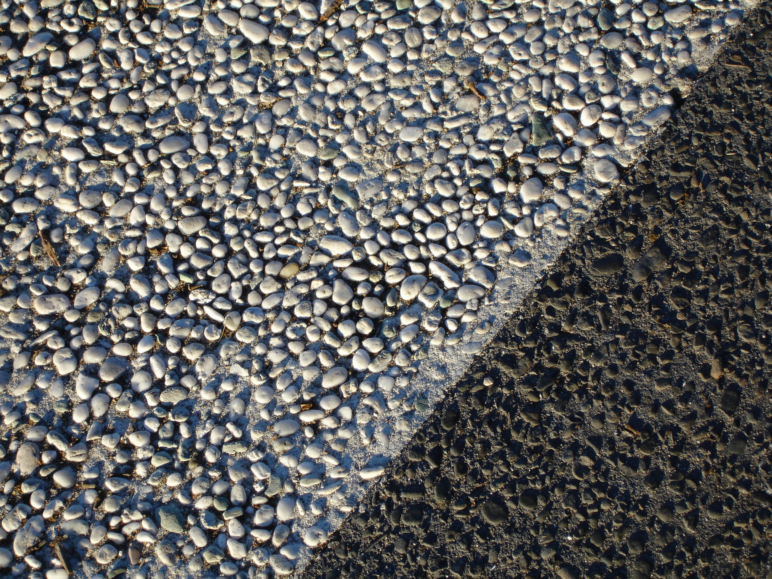 Closeup view of patterned street paving. - Closeup asphalt, cobblestone, gravel, road surface, texture, water, black, gray