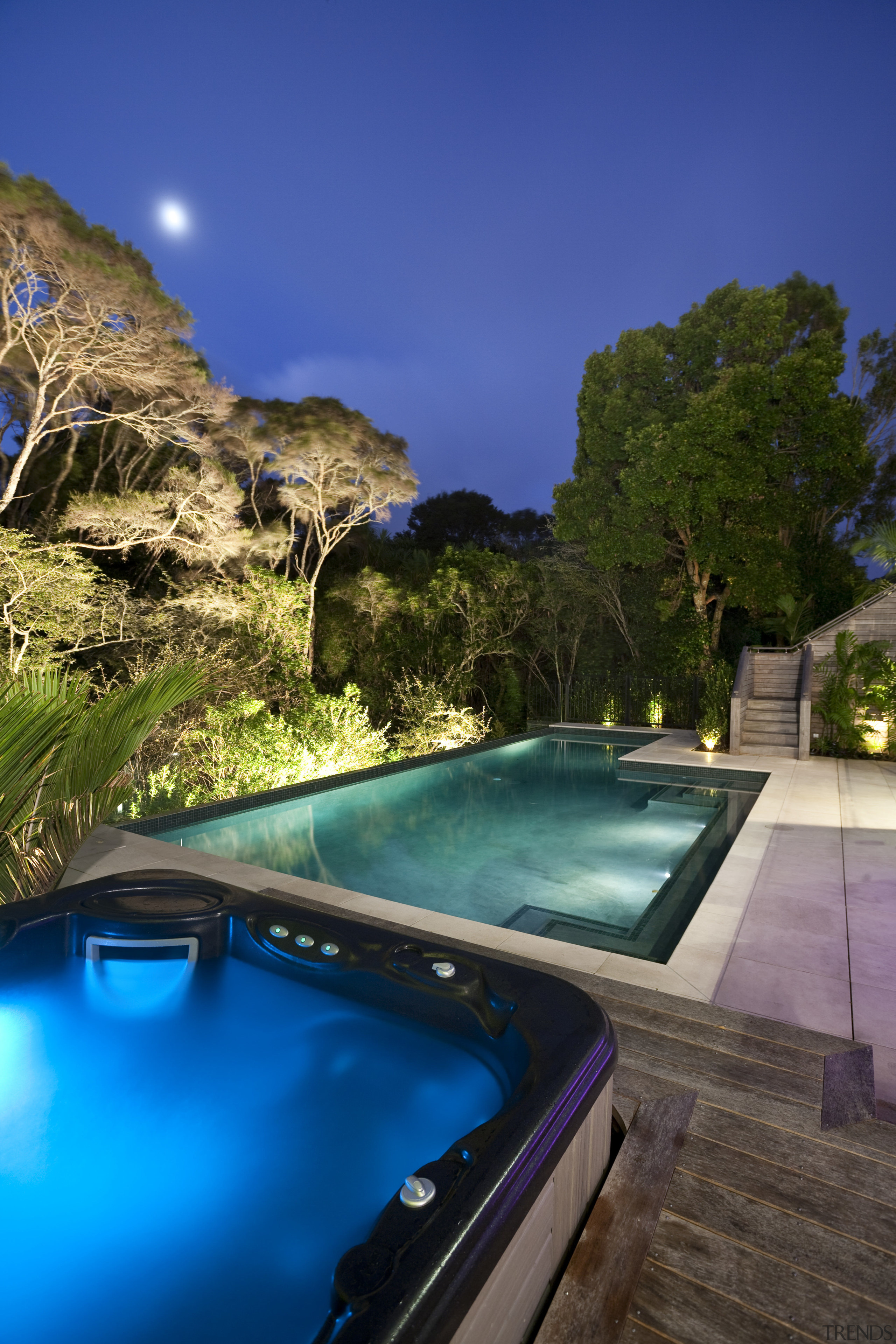 View of sleek poolscape with textured stone wall, estate, leisure, lighting, real estate, reflection, resort, sky, swimming pool, tree, water, blue