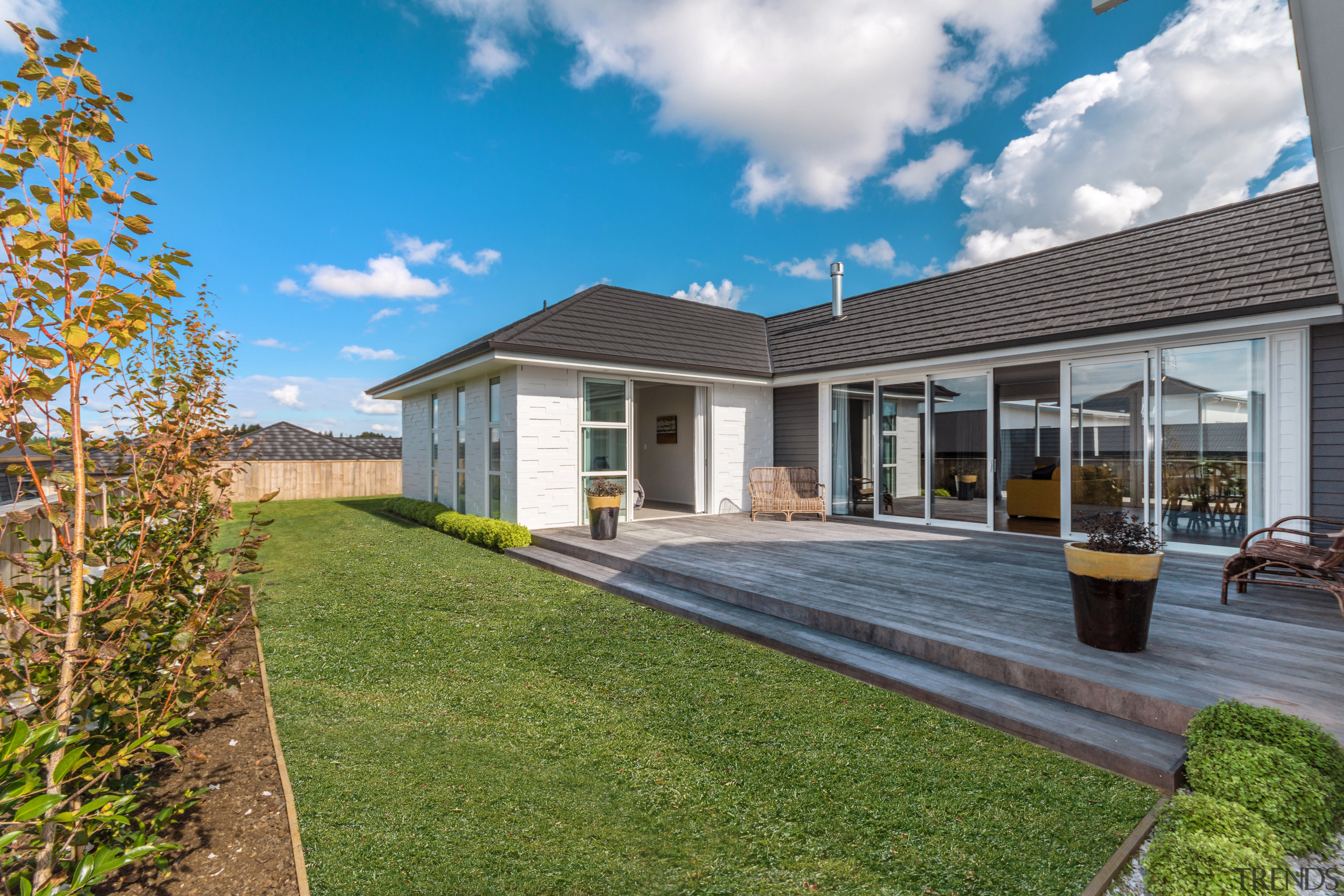 Sheltered on three sides, the deck on this backyard, cottage, elevation, estate, facade, farmhouse, home, house, landscape, property, real estate, residential area, siding, yard