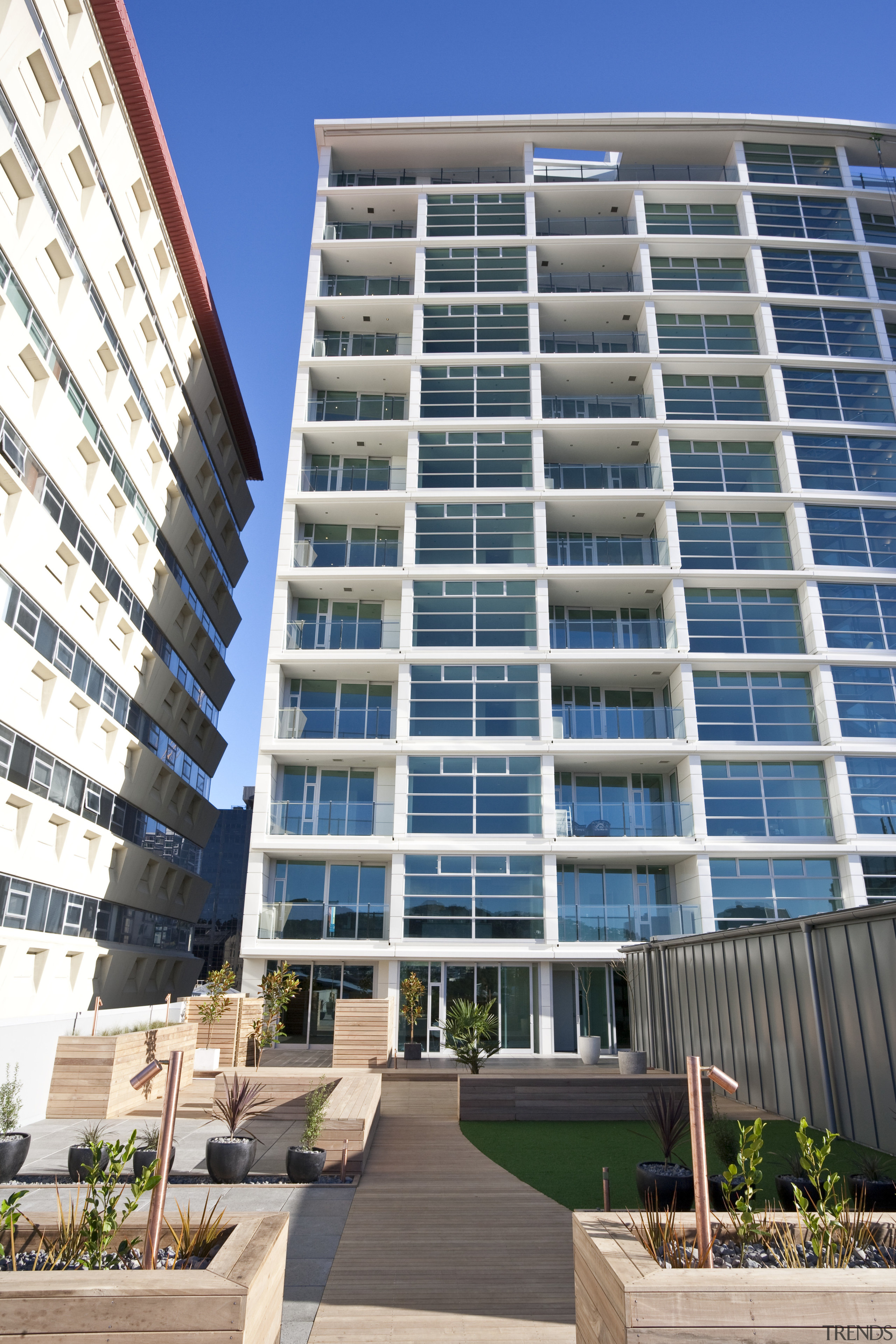 external view of apartment tower above a landscaped apartment, building, commercial building, condominium, corporate headquarters, facade, hotel, metropolitan area, mixed use, property, real estate, residential area, tower block, window, white