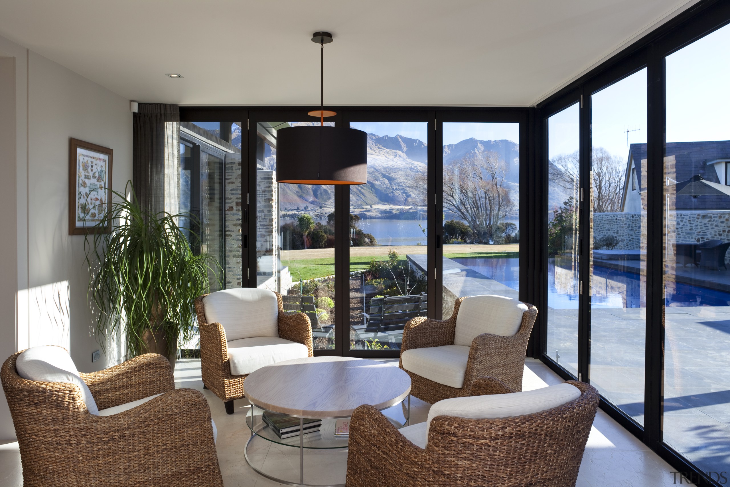 ​​​​​​​Wicker chairs and a circular table have an estate, home, interior design, living room, property, real estate, window, gray