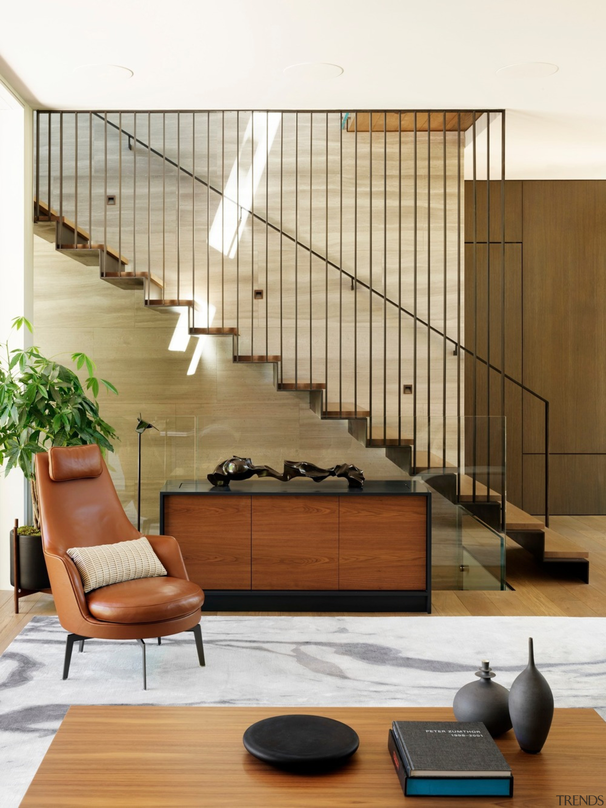 The central stair of this home is the architecture, building, ceiling, design, floor, flooring, furniture, hardwood, home, house, houseplant, interior design, living room, room, stairs, wall, wood, white, brown