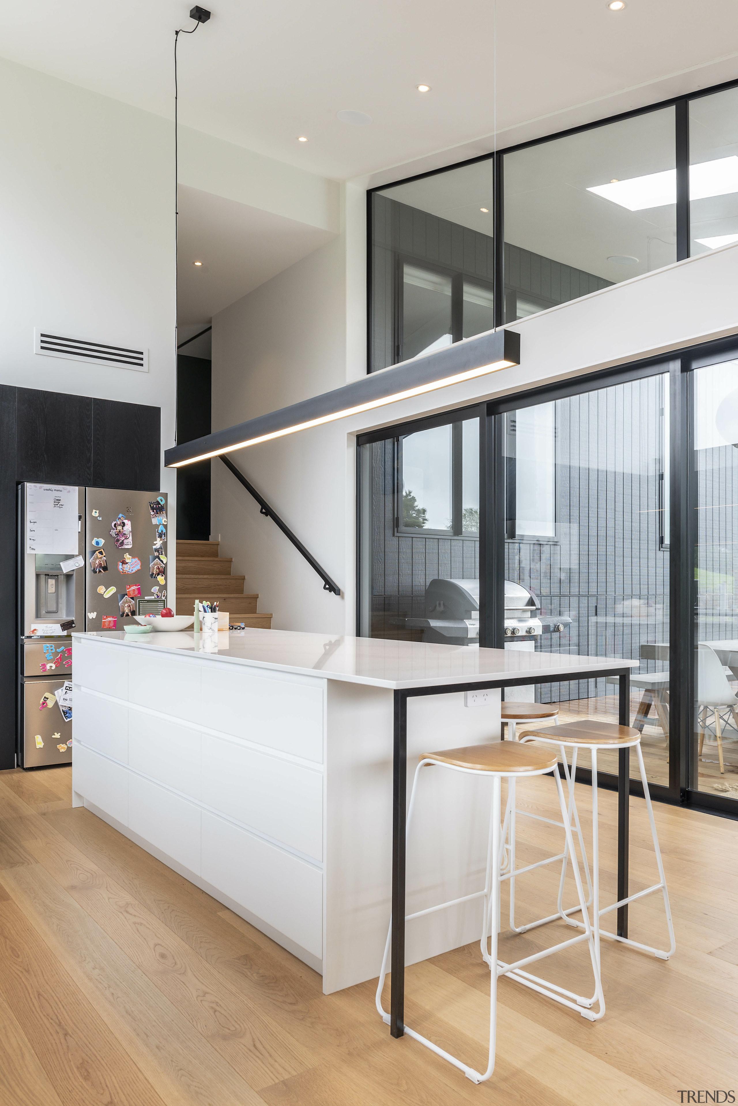 The contemporary kitchen island, with clean-lined pendant overhead, 