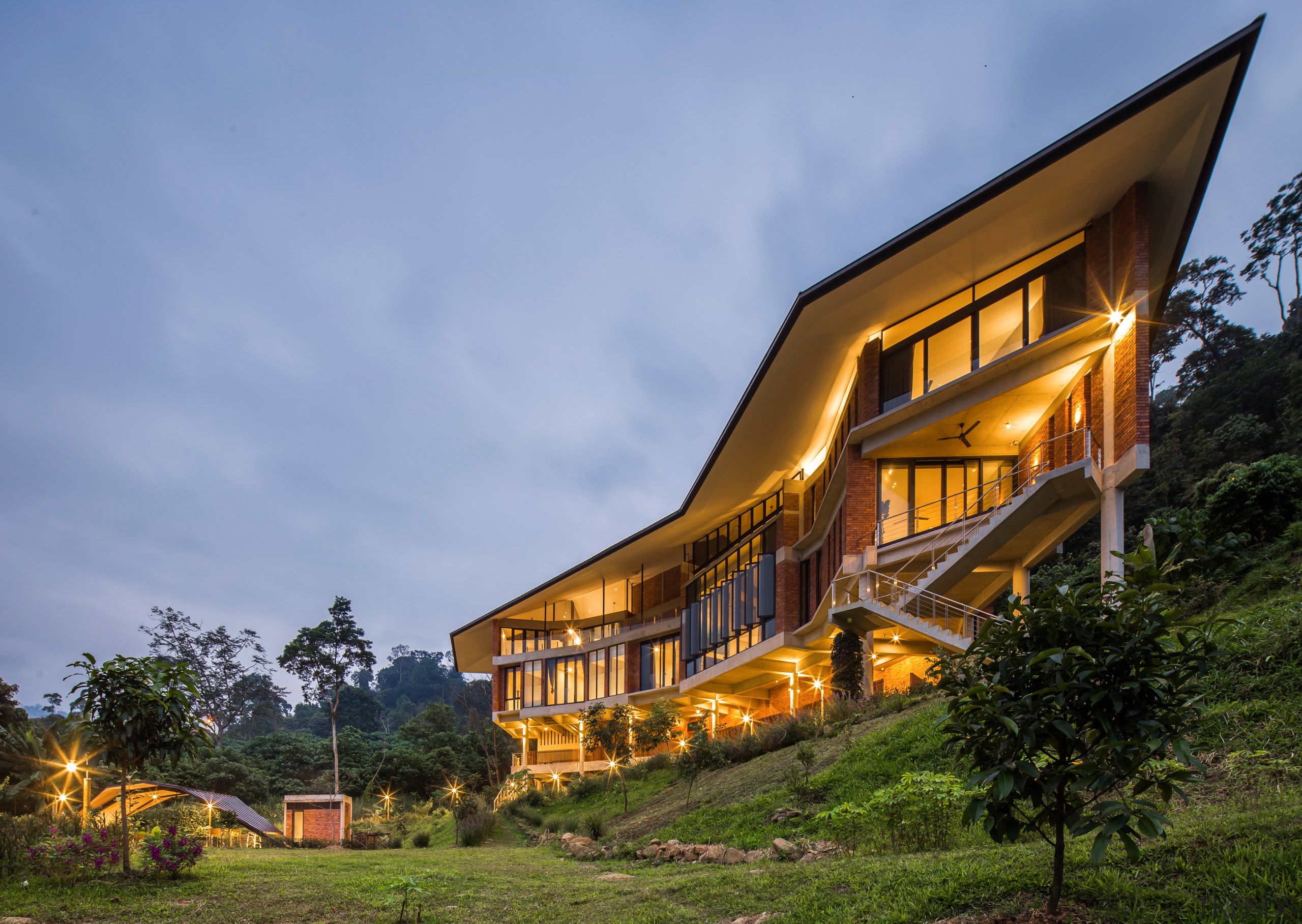 The home grew organically in form as the architecture, building, cloud, cottage, estate, evening, facade, farmhouse, grass, hill station, home, house, landscape, natural landscape, property, real estate, residential area, rural area, sky, tree, teal, brown