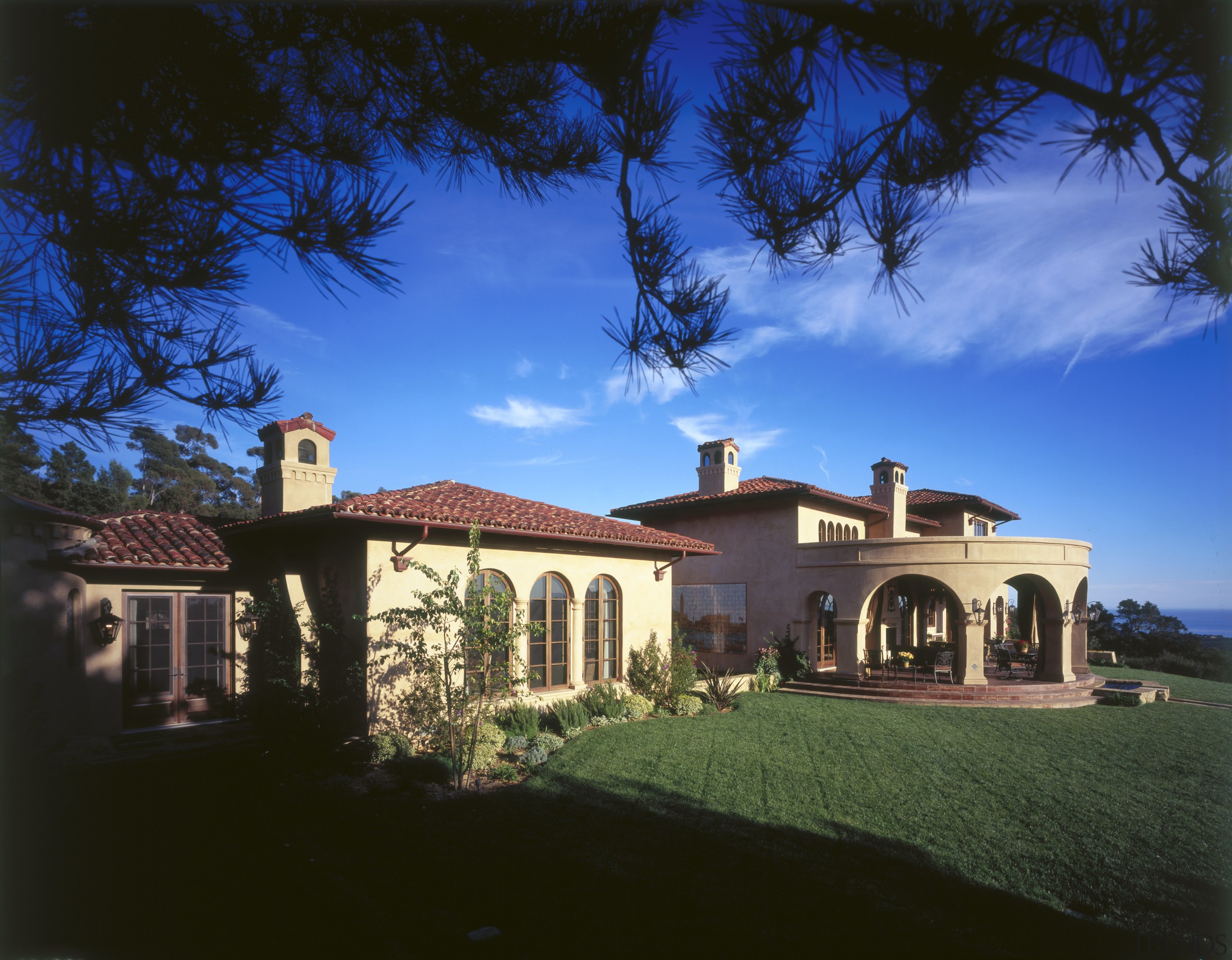an exterior view of this Medtiranean style home architecture, building, cloud, cottage, estate, evening, facade, hacienda, home, house, landscape lighting, lighting, mansion, property, real estate, residential area, roof, sky, villa, black, blue