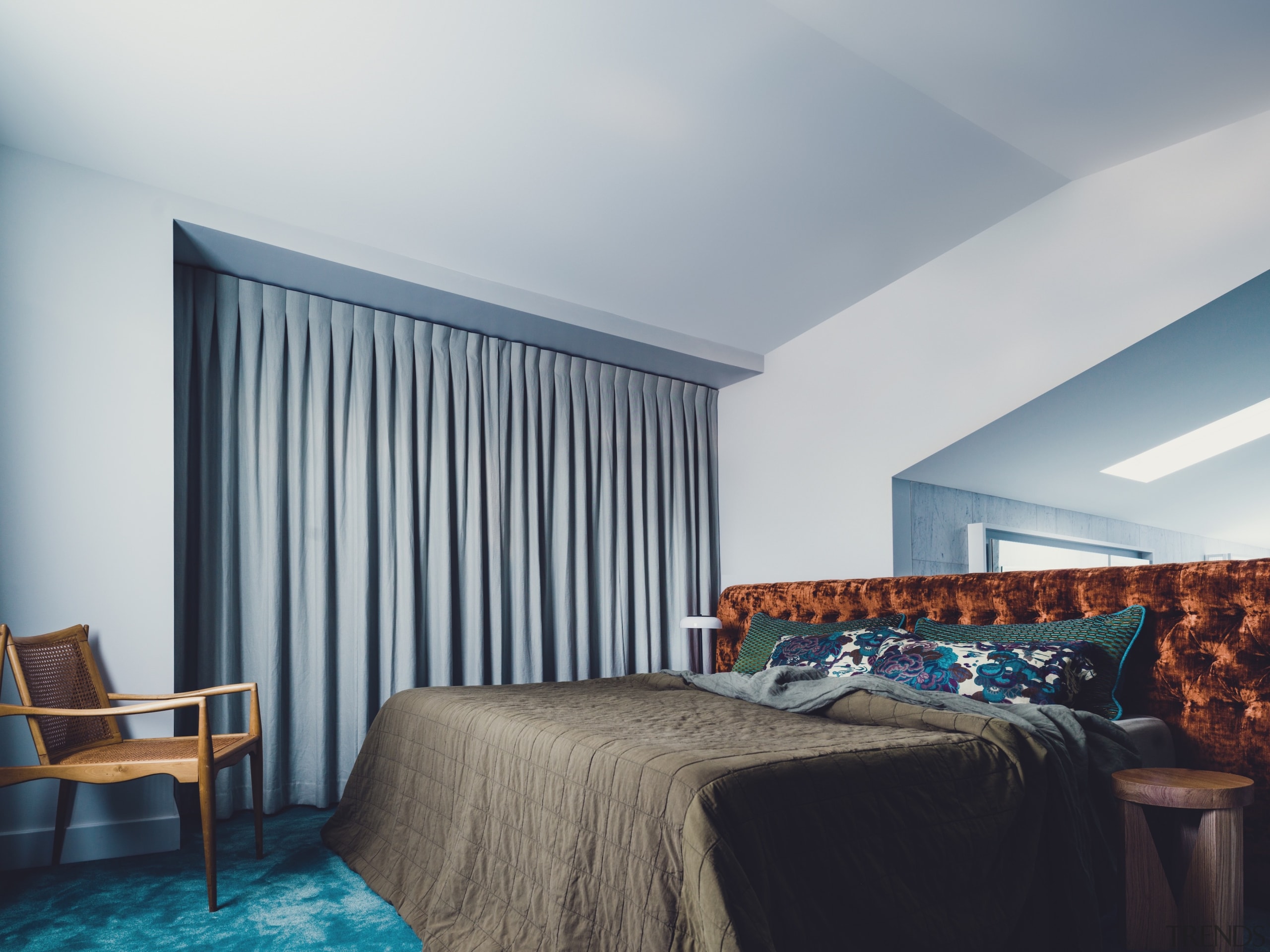 A custom bedhead in burnt-orange velvet disguises the 