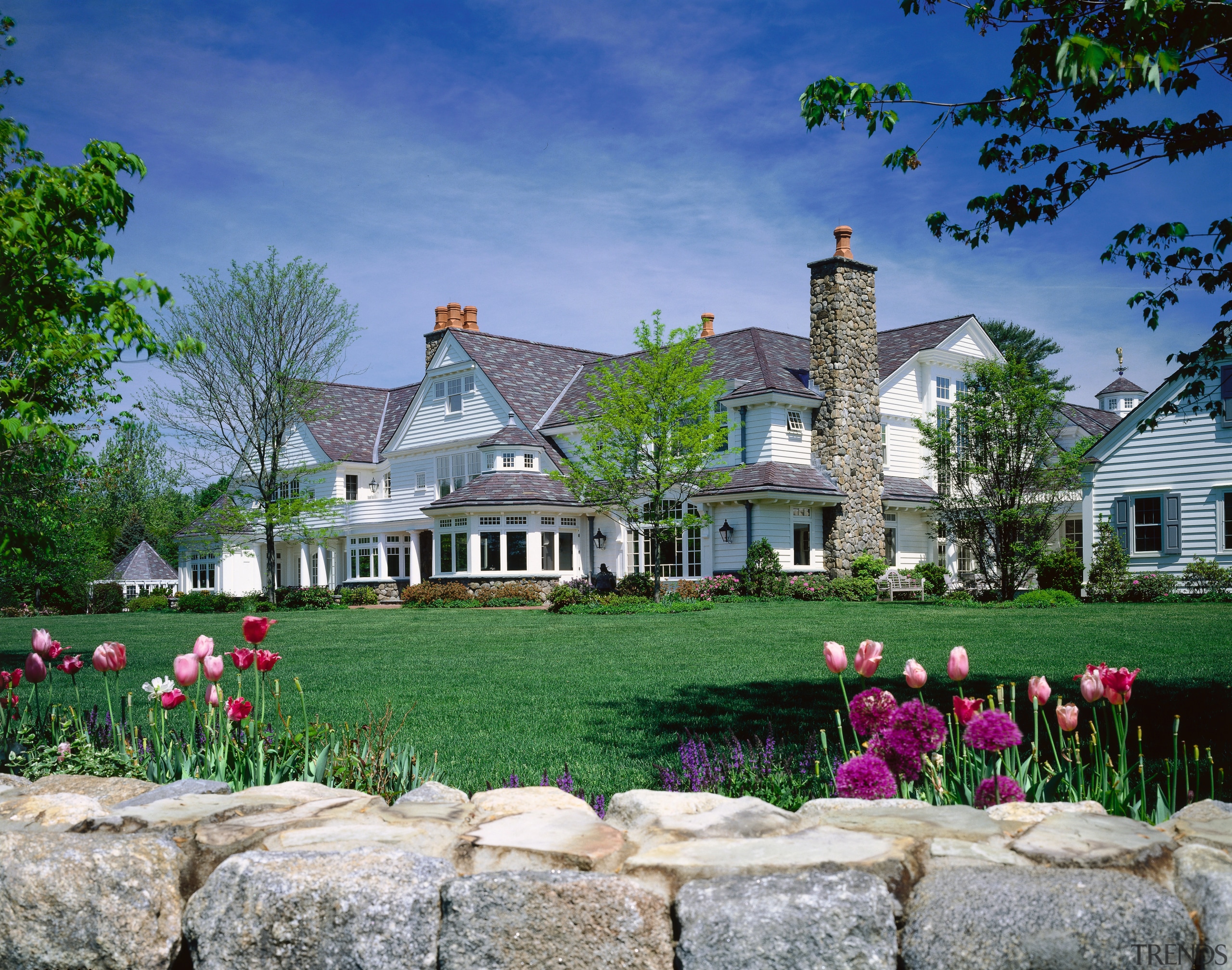 Exterior view of large traditional style home with cottage, estate, farm, farmhouse, flower, garden, grass, home, house, landscape, landscaping, lawn, mansion, meadow, plant, plantation, property, real estate, sky, tree, blue