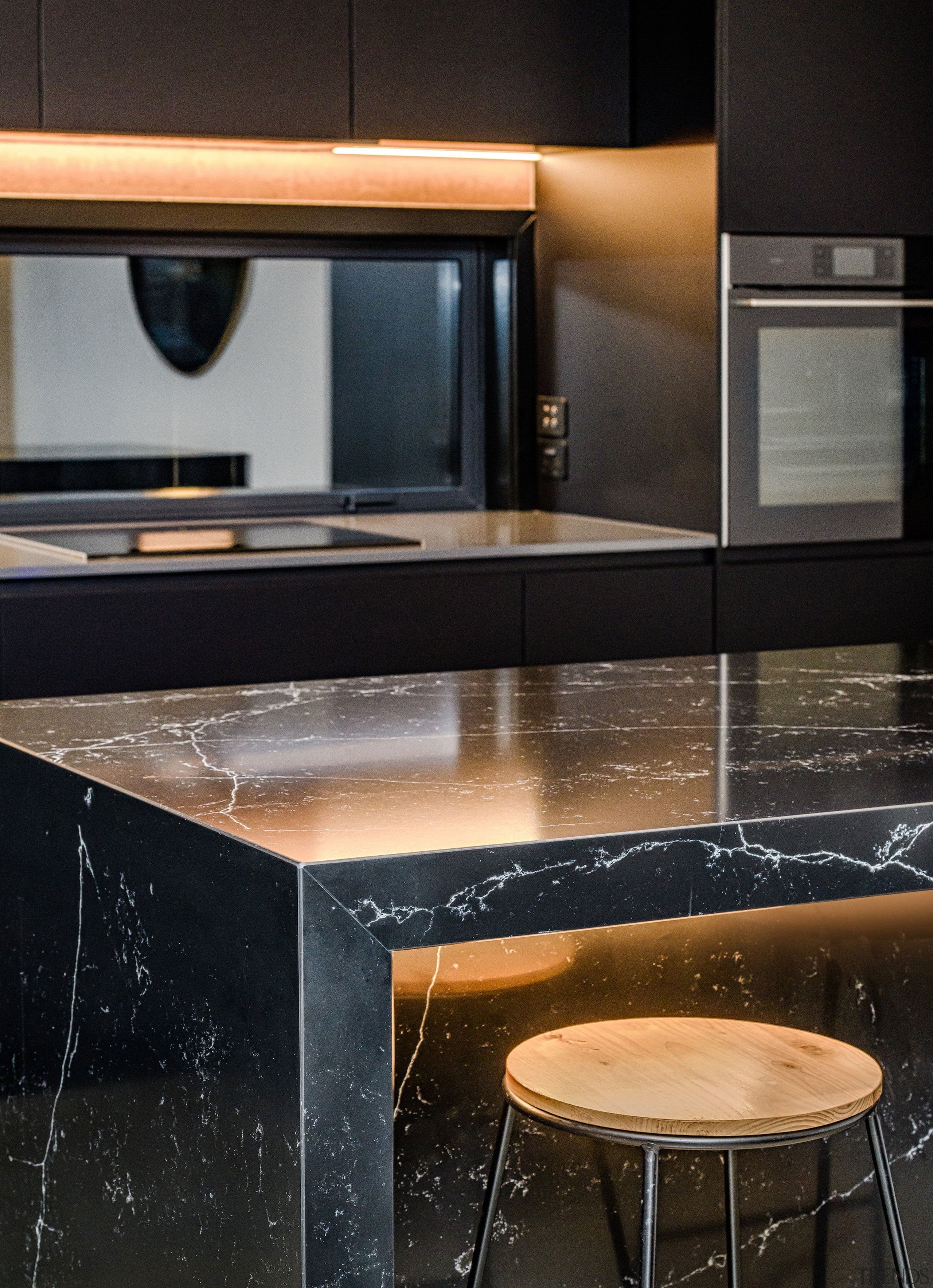 The black stone island is under-lit for dramatic architecture, building, cabinetry, countertop, design, desk, floor, flooring, furniture, glass, granite, home, house, interior design, kitchen, marble, material property, property, room, table, tile, black