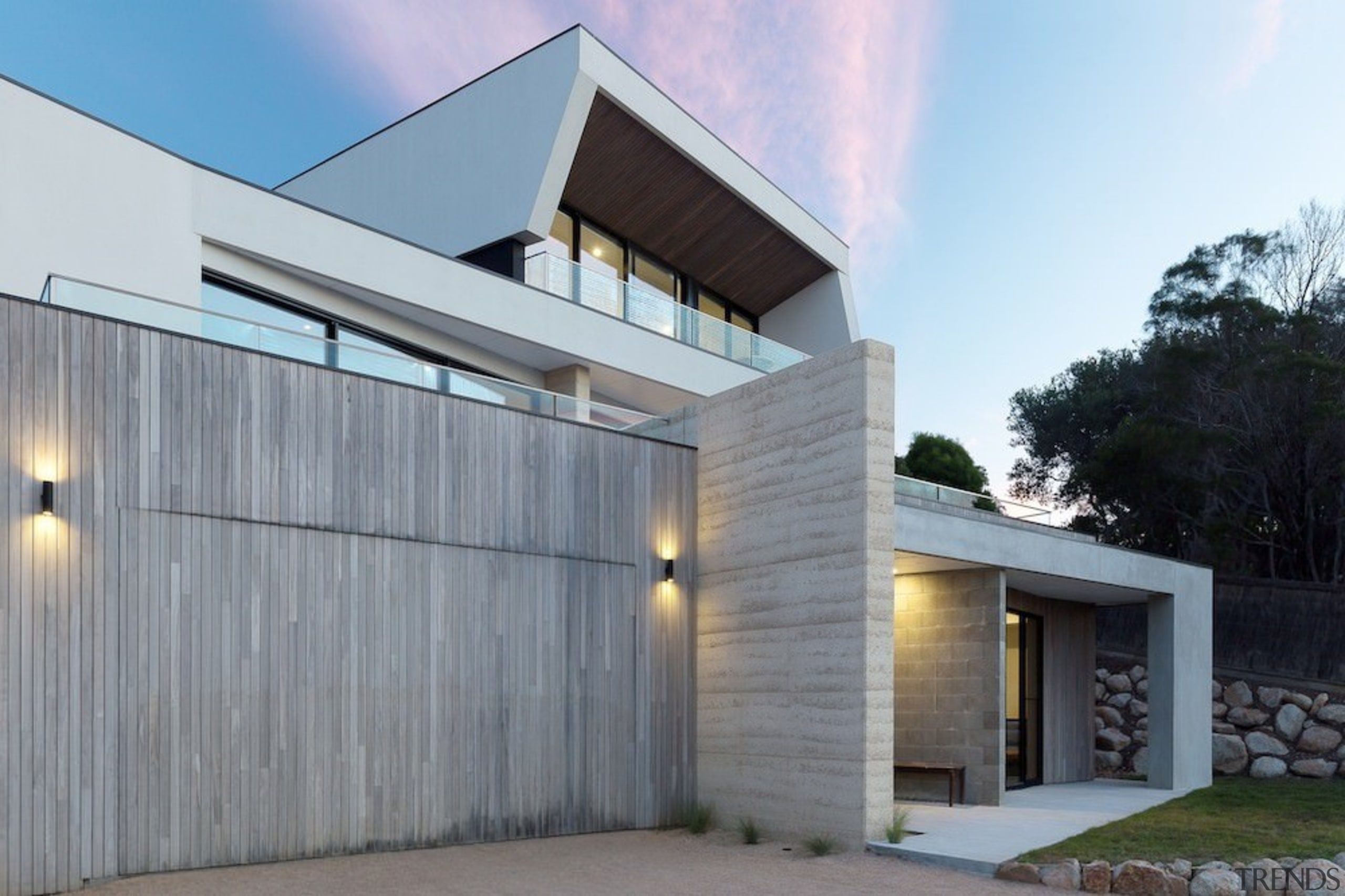 The exterior features concrete, wood, rock and glass architecture, building, elevation, facade, home, house, property, real estate, residential area, siding, gray