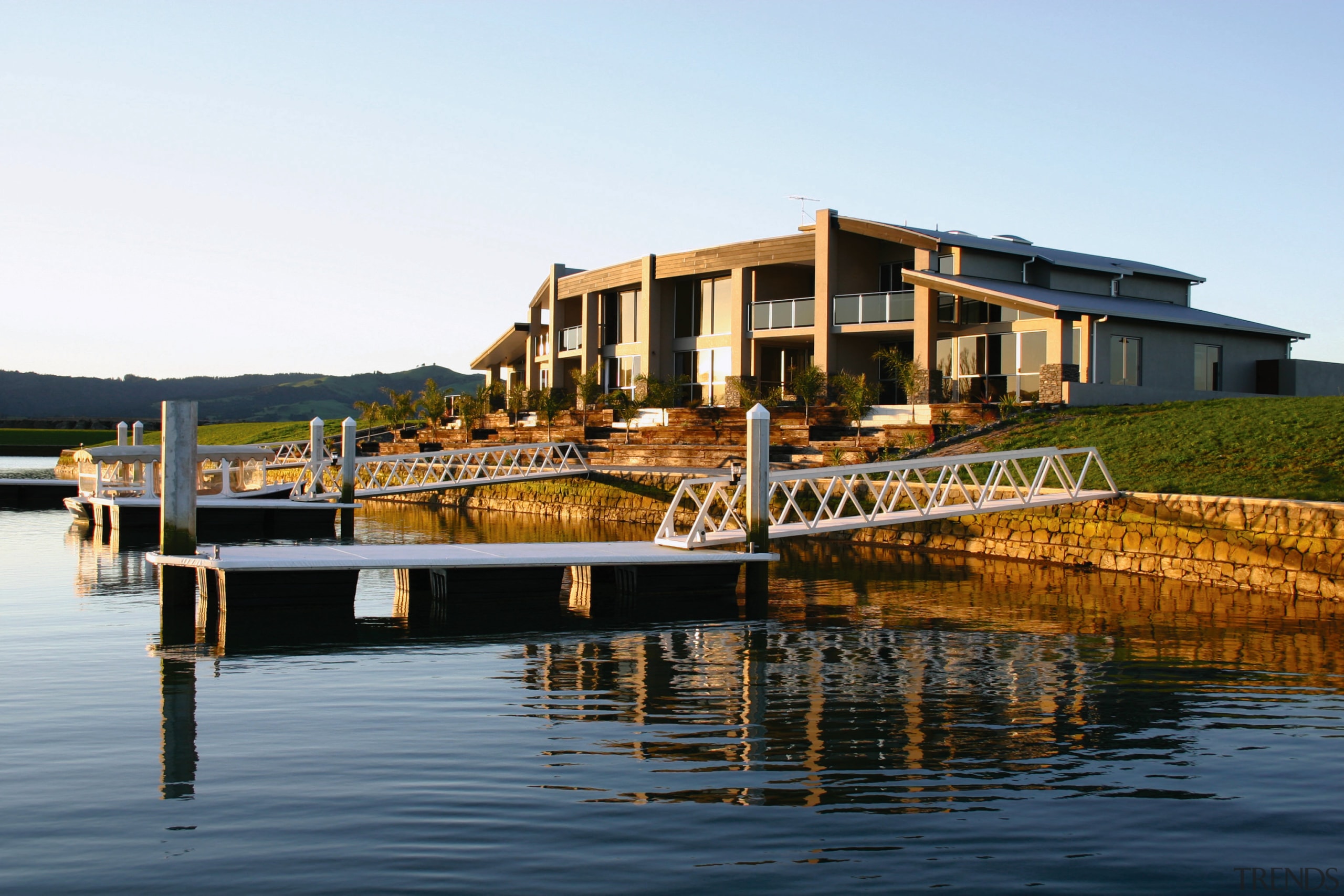 A exterior view of a holiday home. with cottage, dock, estate, home, house, marina, property, real estate, reflection, sky, villa, water, waterway, white