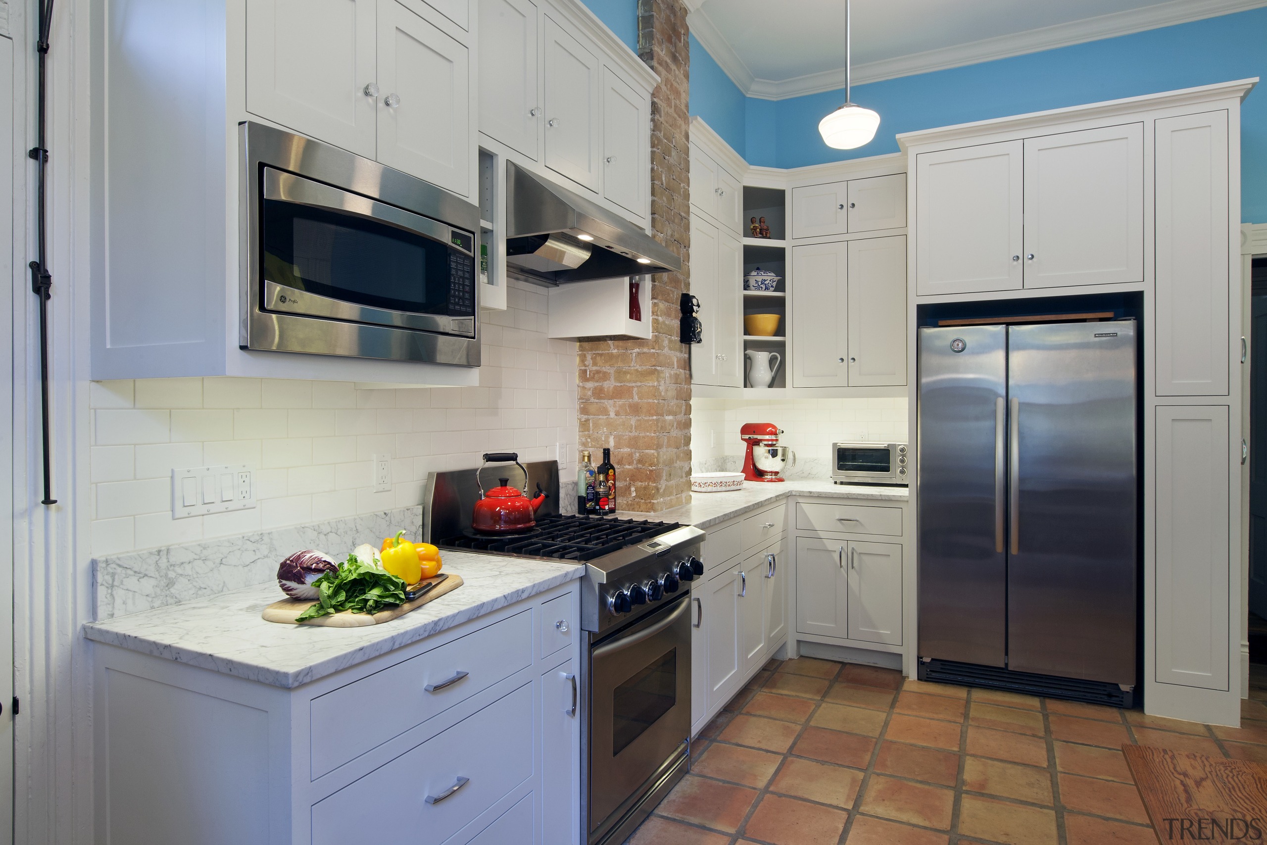 White kitchen with exposed brick chimney, blue walls, cabinetry, countertop, home appliance, kitchen, major appliance, real estate, room, gray