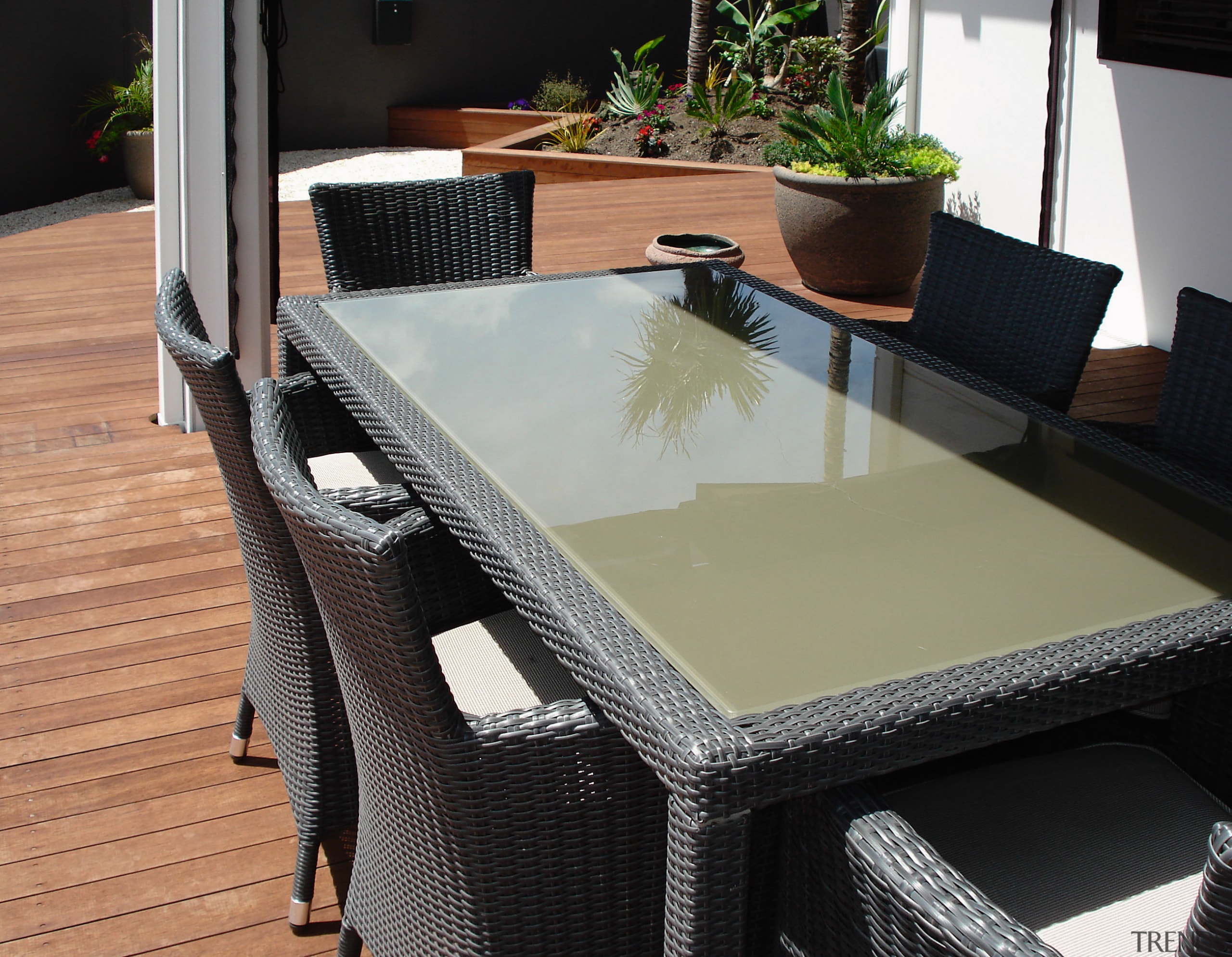 View of the outdoor dining area featuring table, chair, floor, flooring, furniture, outdoor furniture, table, wicker, black