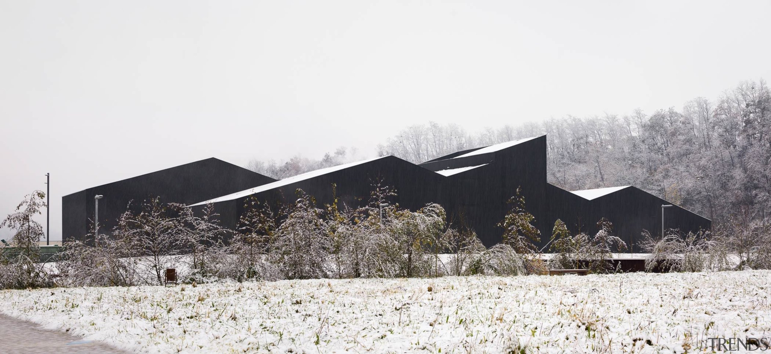 The building almost looks like a rock formation architecture, barn, farmhouse, home, house, snow, tree, winter, white