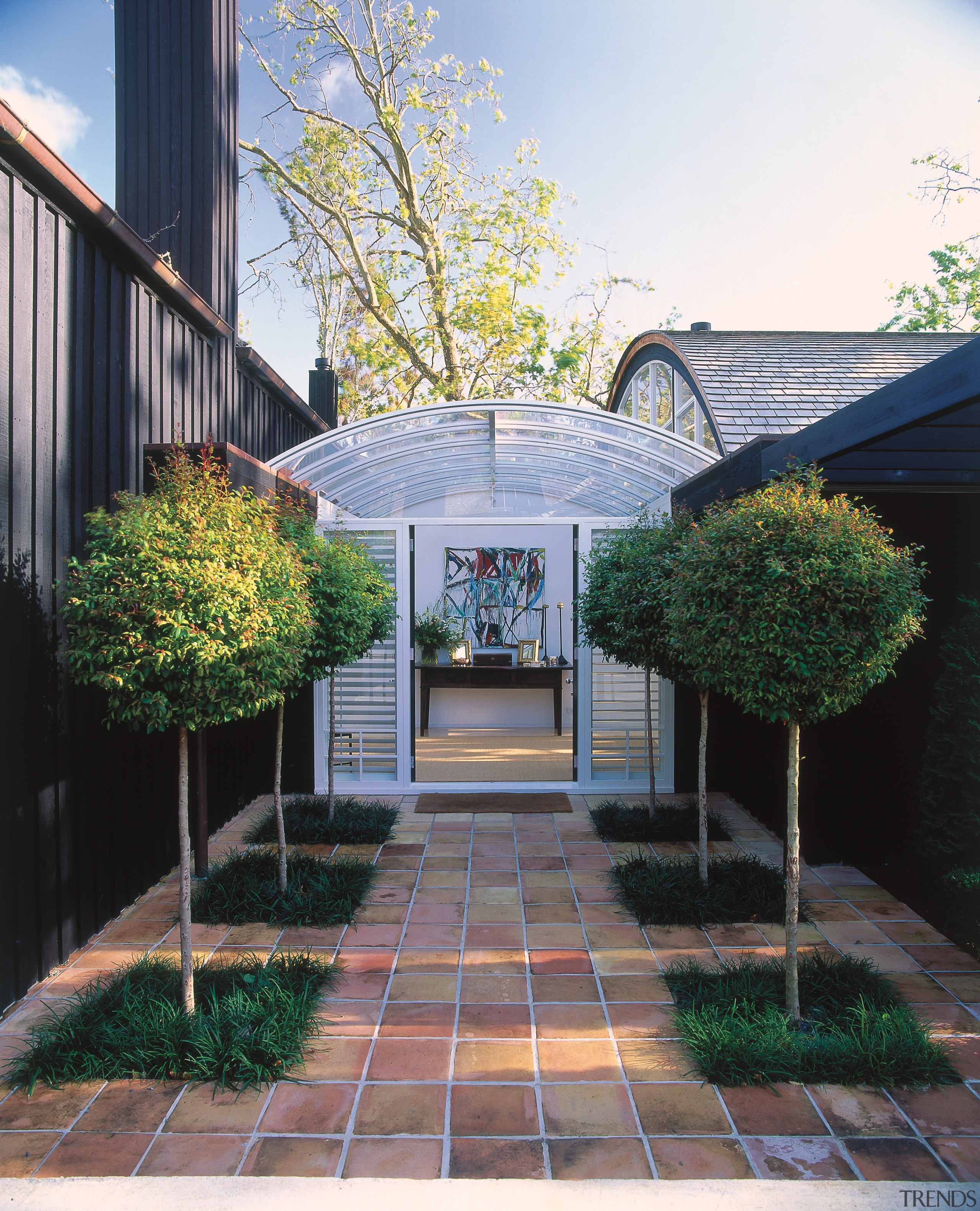 An exterior view of this home designed by architecture, backyard, courtyard, facade, home, house, landscaping, outdoor structure, real estate, residential area, tree, walkway, yard, white, black