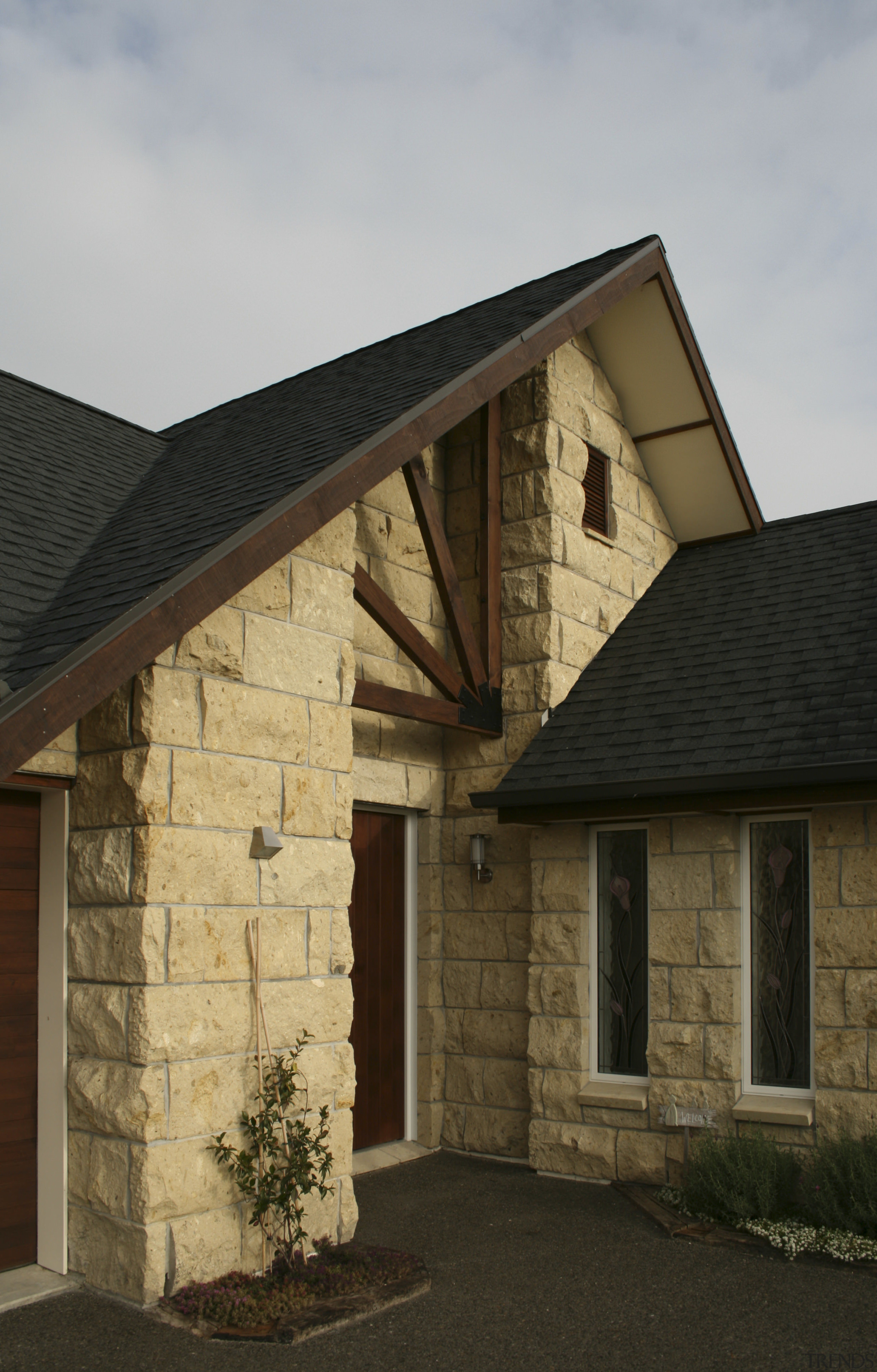 Exterior view of a home which features block building, cottage, estate, facade, farmhouse, home, house, property, real estate, roof, siding, wall, window, wood, brown, gray