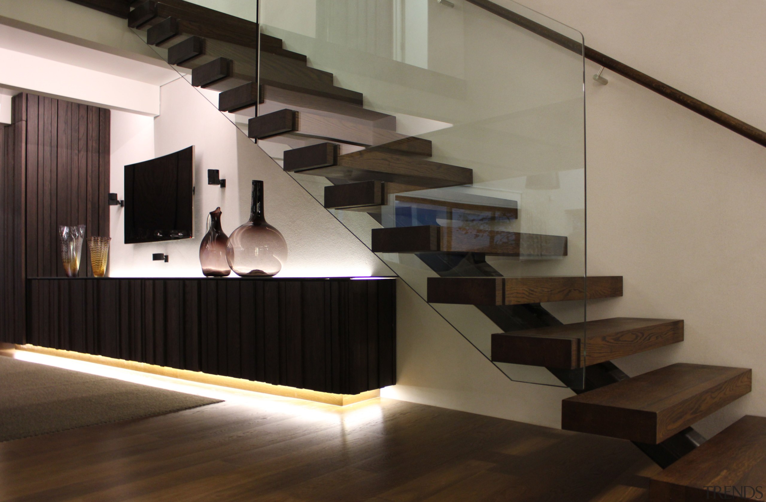 This long entertainment unit is one of the floor, flooring, handrail, hardwood, interior design, lobby, product design, property, stairs, black, gray