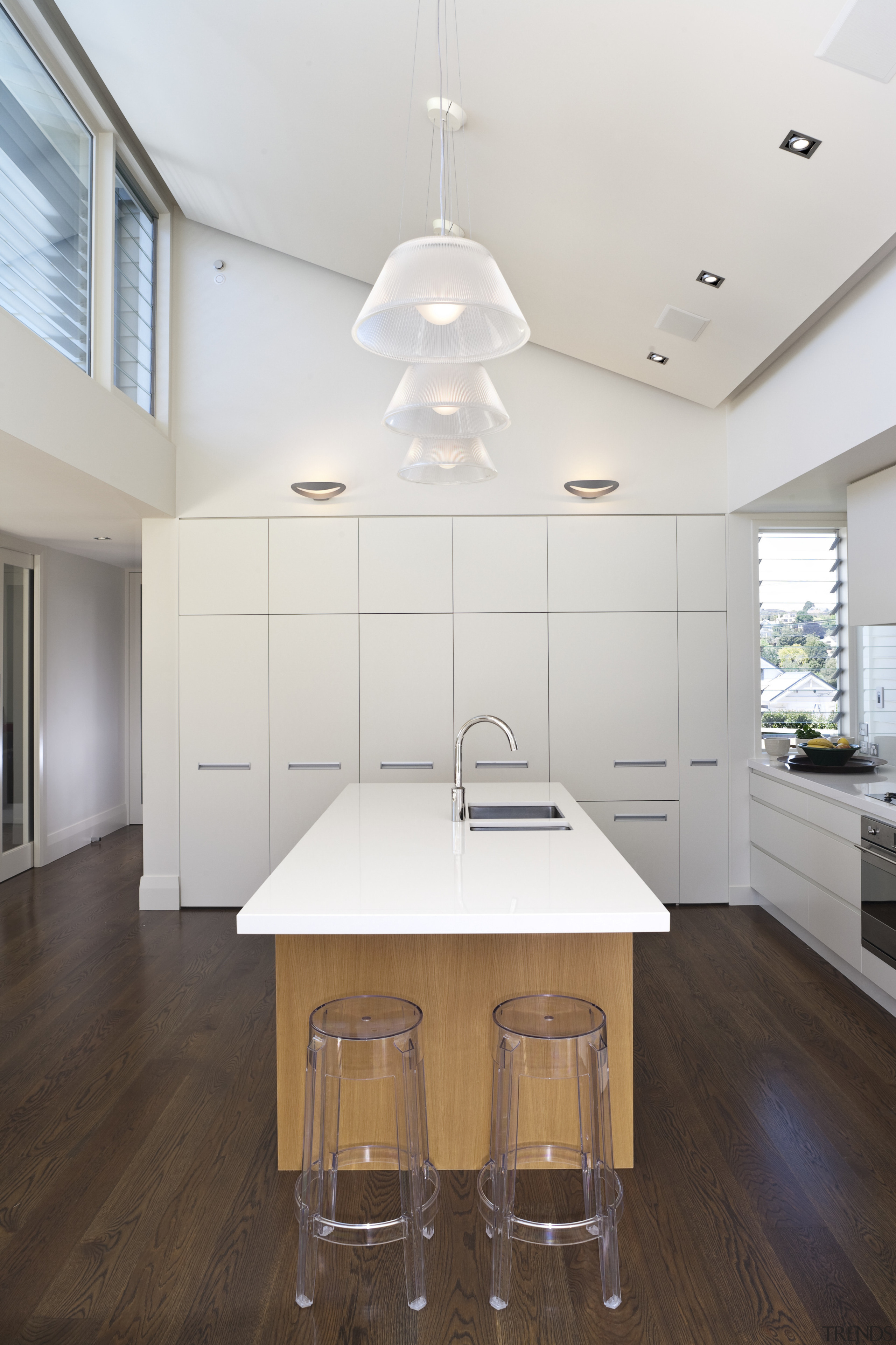 Sleek white lacquered cabinetry wraps the sides of ceiling, countertop, daylighting, floor, flooring, hardwood, home, house, interior design, kitchen, laminate flooring, real estate, room, table, wood flooring, white