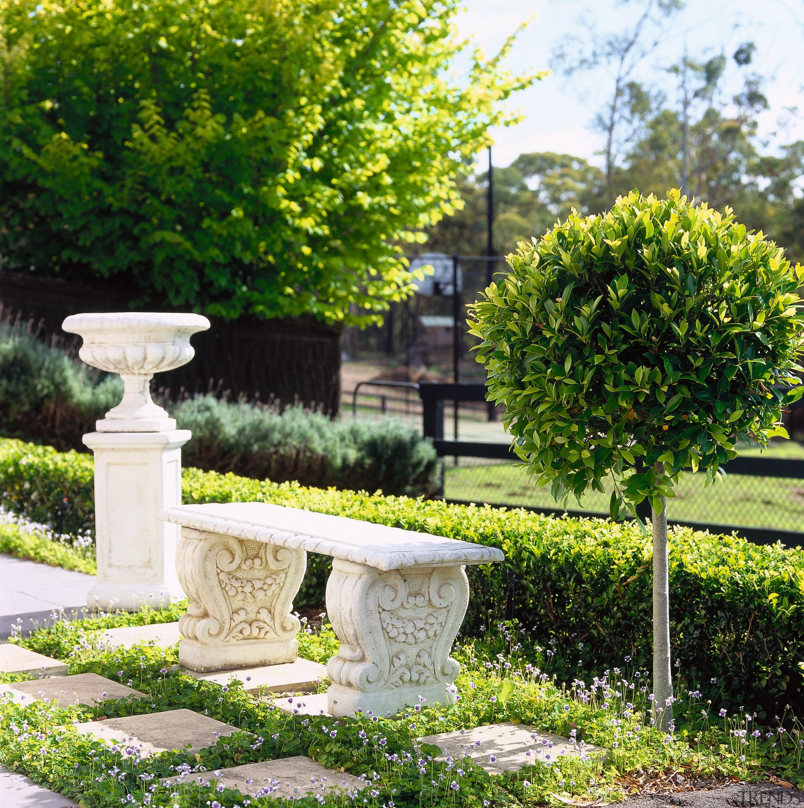 Close up view of a white stone bench flowerpot, garden, grass, hedge, houseplant, landscape, landscaping, park, plant, shrub, tree, walkway, green