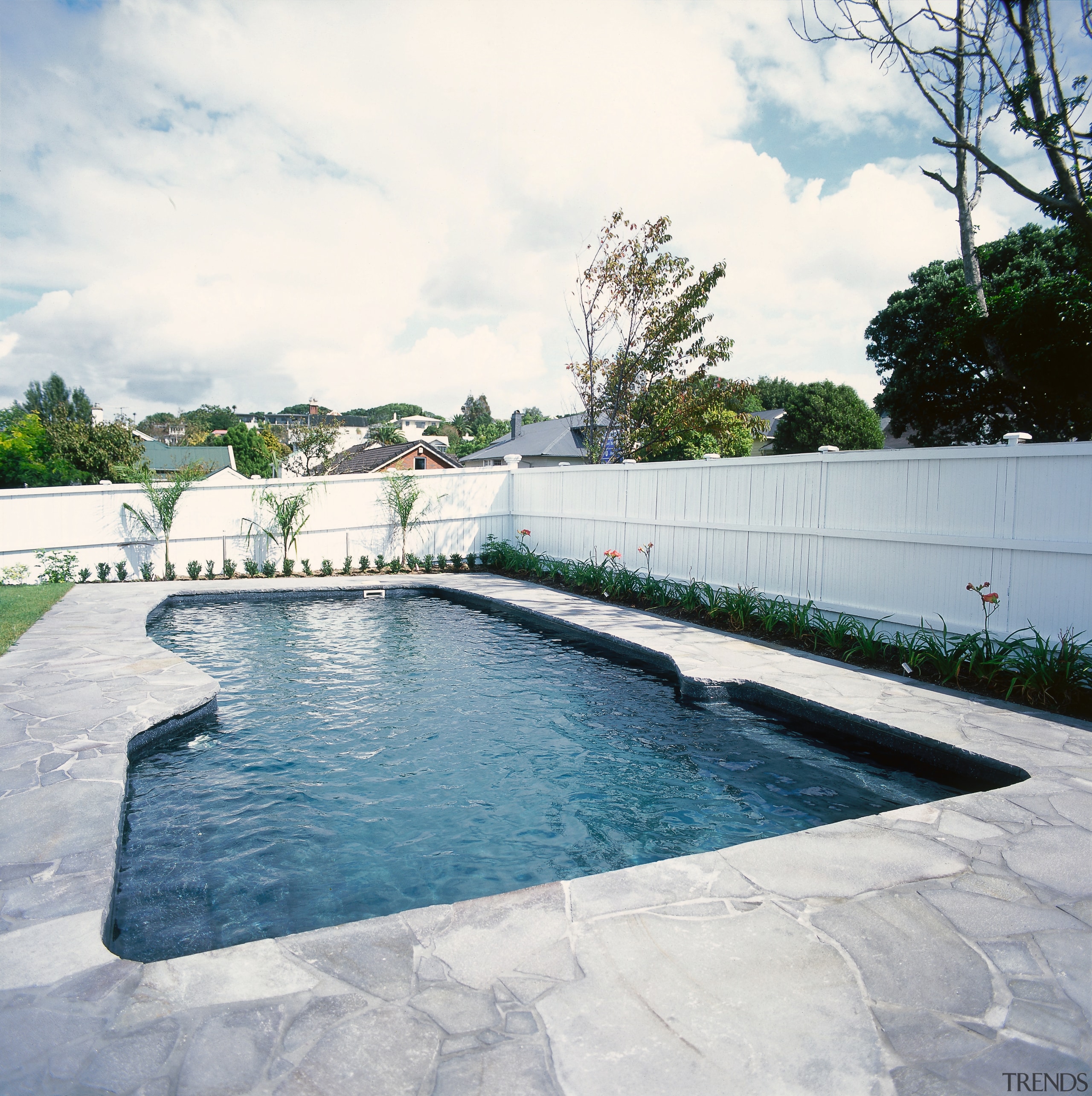 A view of a swimming pool. - A backyard, estate, fence, leisure, outdoor structure, property, real estate, swimming pool, wall, water, white, gray