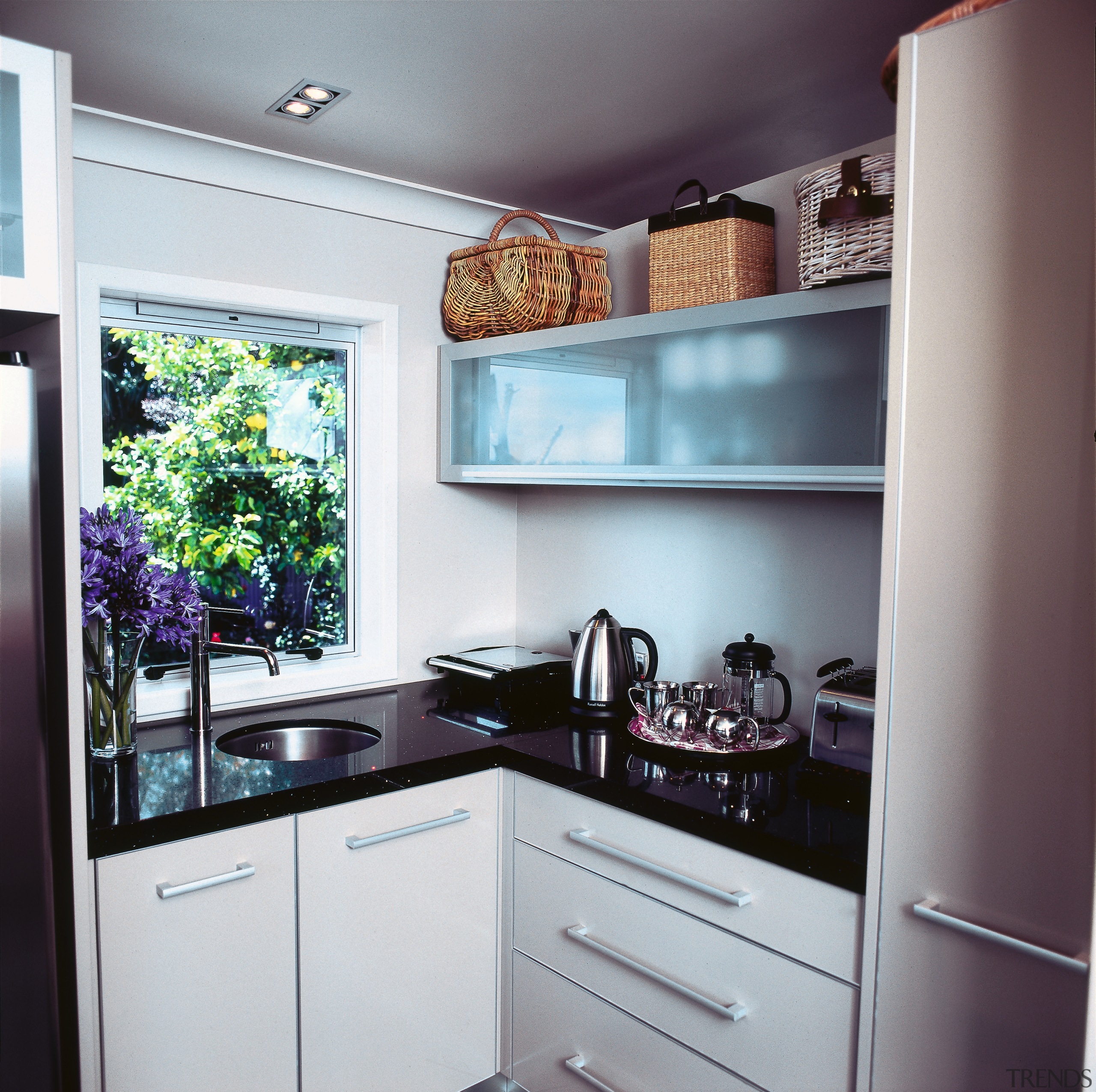 Corner of kitchen area with black coloured benchtop, cabinetry, countertop, cuisine classique, furniture, home, home appliance, interior design, kitchen, refrigerator, room, gray