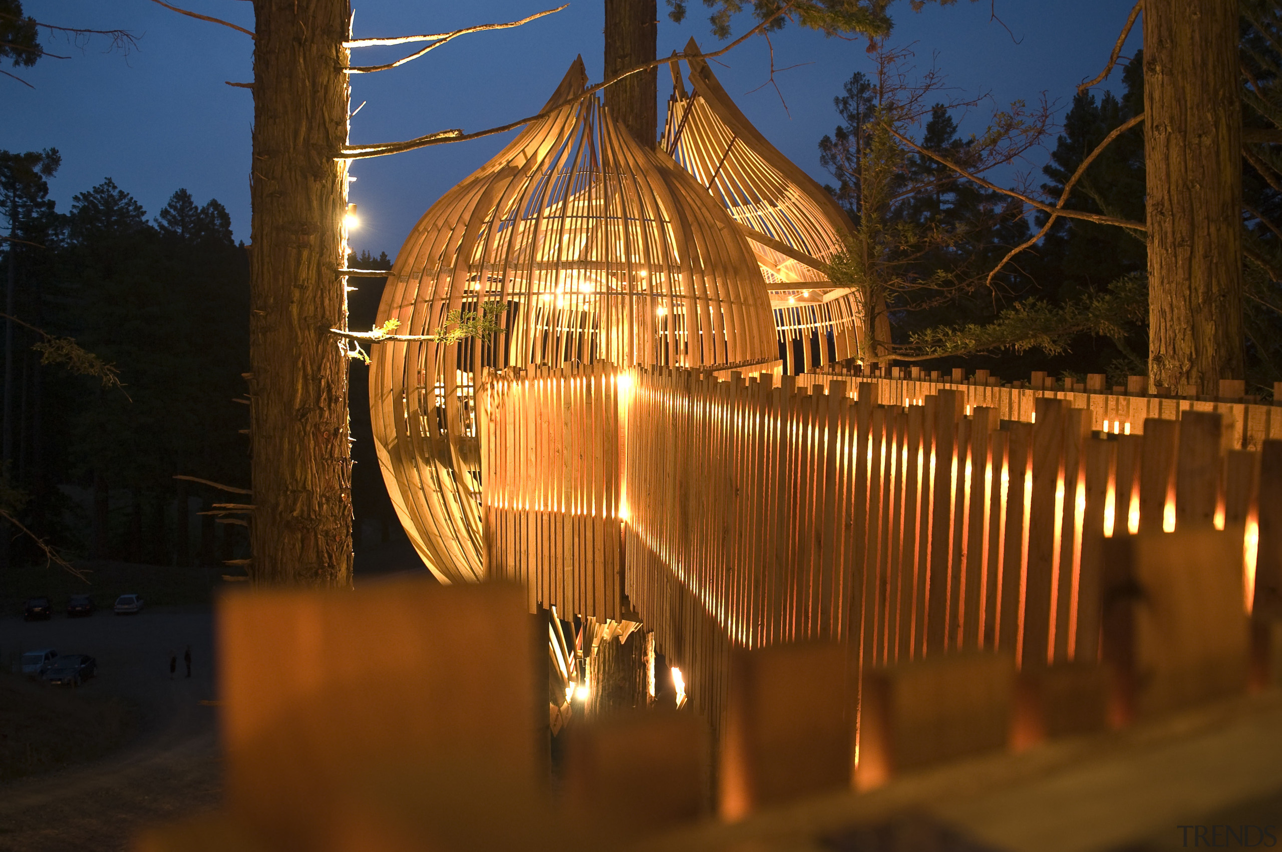 Image of the Yellow Treehouse restaurant which has architecture, evening, light, lighting, night, reflection, sky, tourist attraction, tree, wood, brown