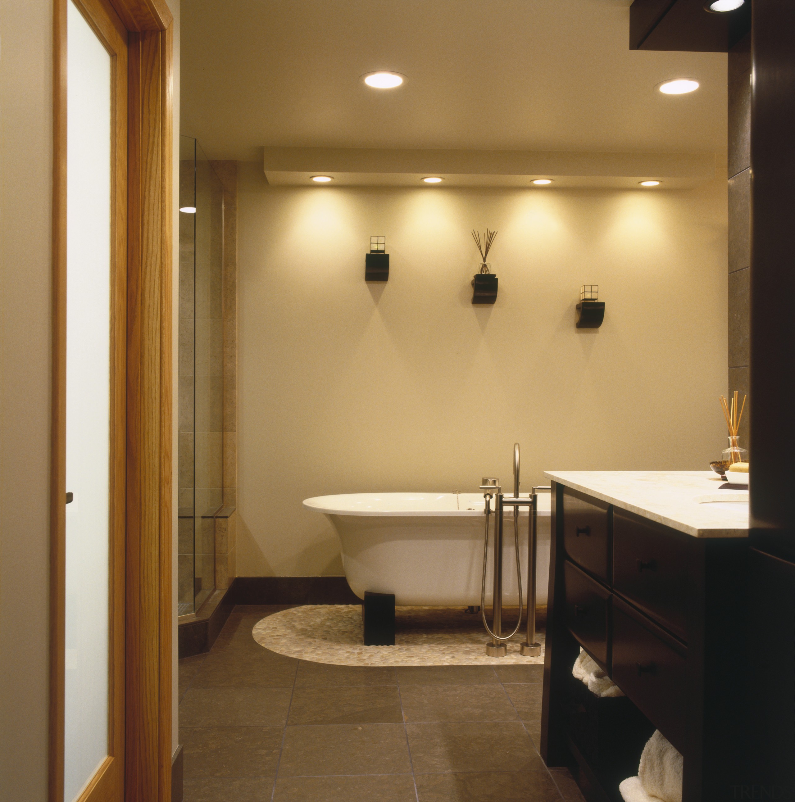 A soaking tub on a bed of river bathroom, ceiling, floor, flooring, interior design, light fixture, lighting, plumbing fixture, real estate, room, sink, brown, orange