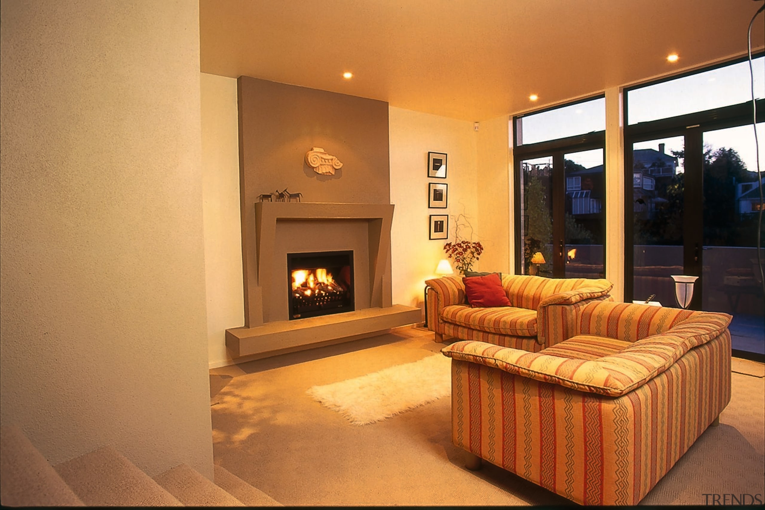 Lounge room with fire set into concrete surround, ceiling, fireplace, floor, flooring, hearth, home, interior design, living room, property, real estate, room, orange, brown