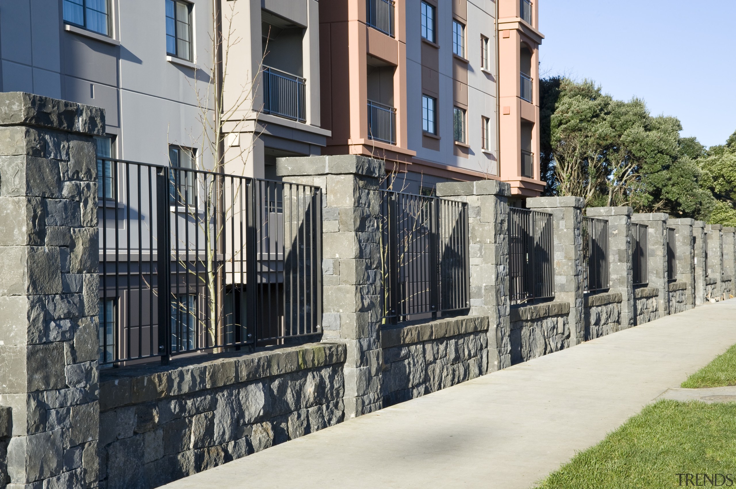 View of the stone wall with metal sections building, facade, fence, handrail, home fencing, house, iron, neighbourhood, outdoor structure, property, real estate, residential area, walkway, wall, black, gray