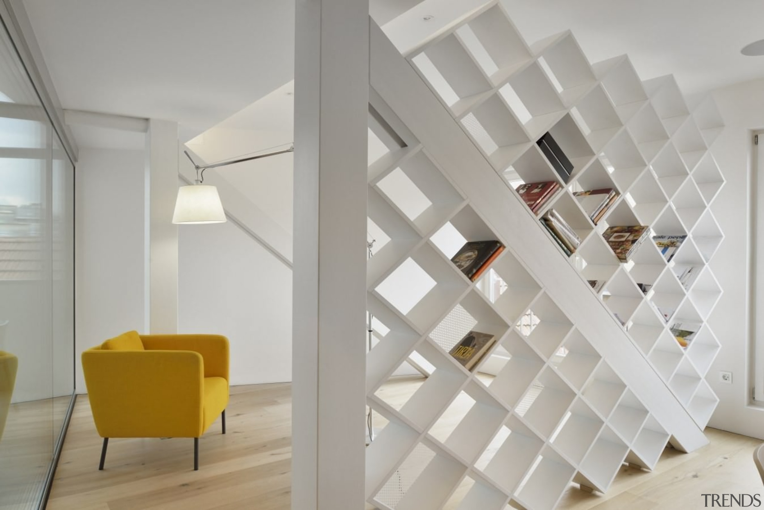 A bookshelf breaks up this large living space architecture, ceiling, daylighting, floor, home, interior design, loft, product design, shelf, stairs, wall, gray