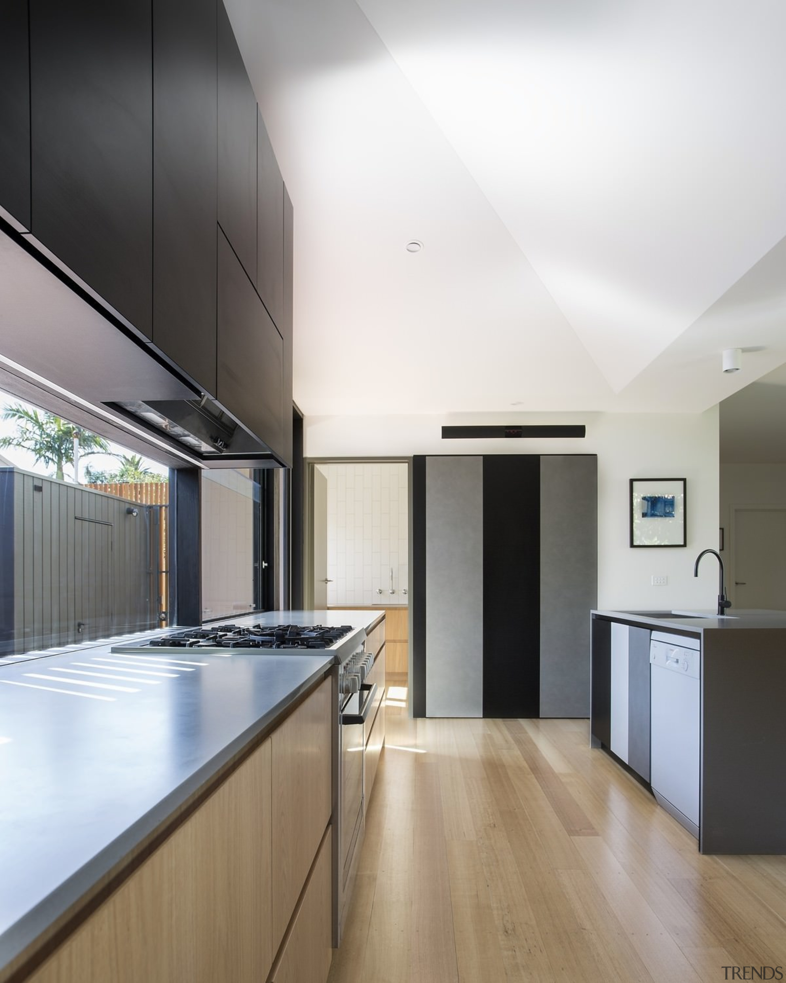 The island conceals the dishwasher and sink, while architecture, cabinetry, ceiling, countertop, daylighting, floor, hardwood, house, interior design, kitchen, laminate flooring, real estate, wood flooring, white