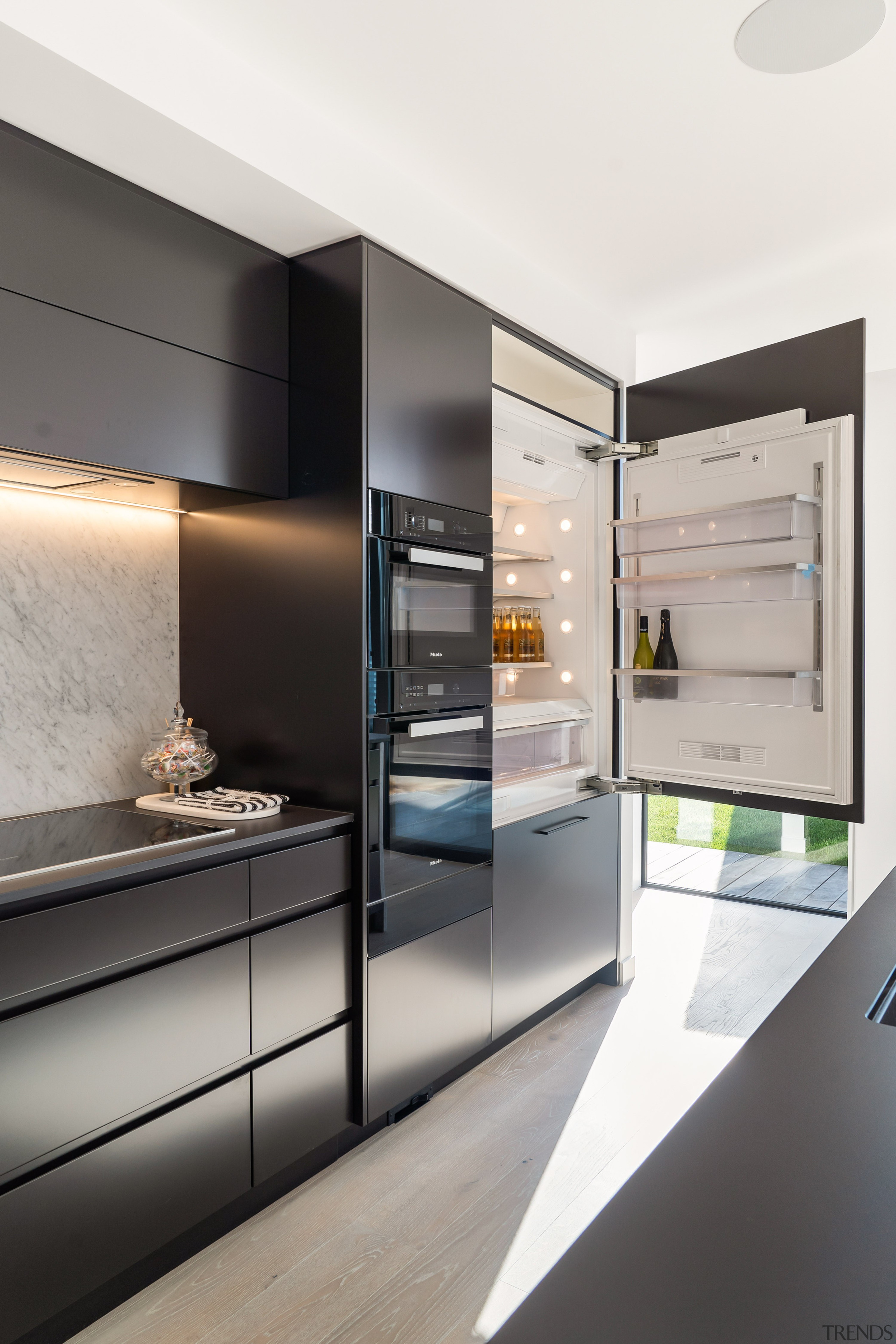 The sleek black handleless kitchen has top-of-the-line Miele apartment, architecture, building, cabinetry, ceiling, countertop, cupboard, design, floor, flooring, furniture, home, house, interior design, kitchen, material property, property, real estate, room, wall, white, gray