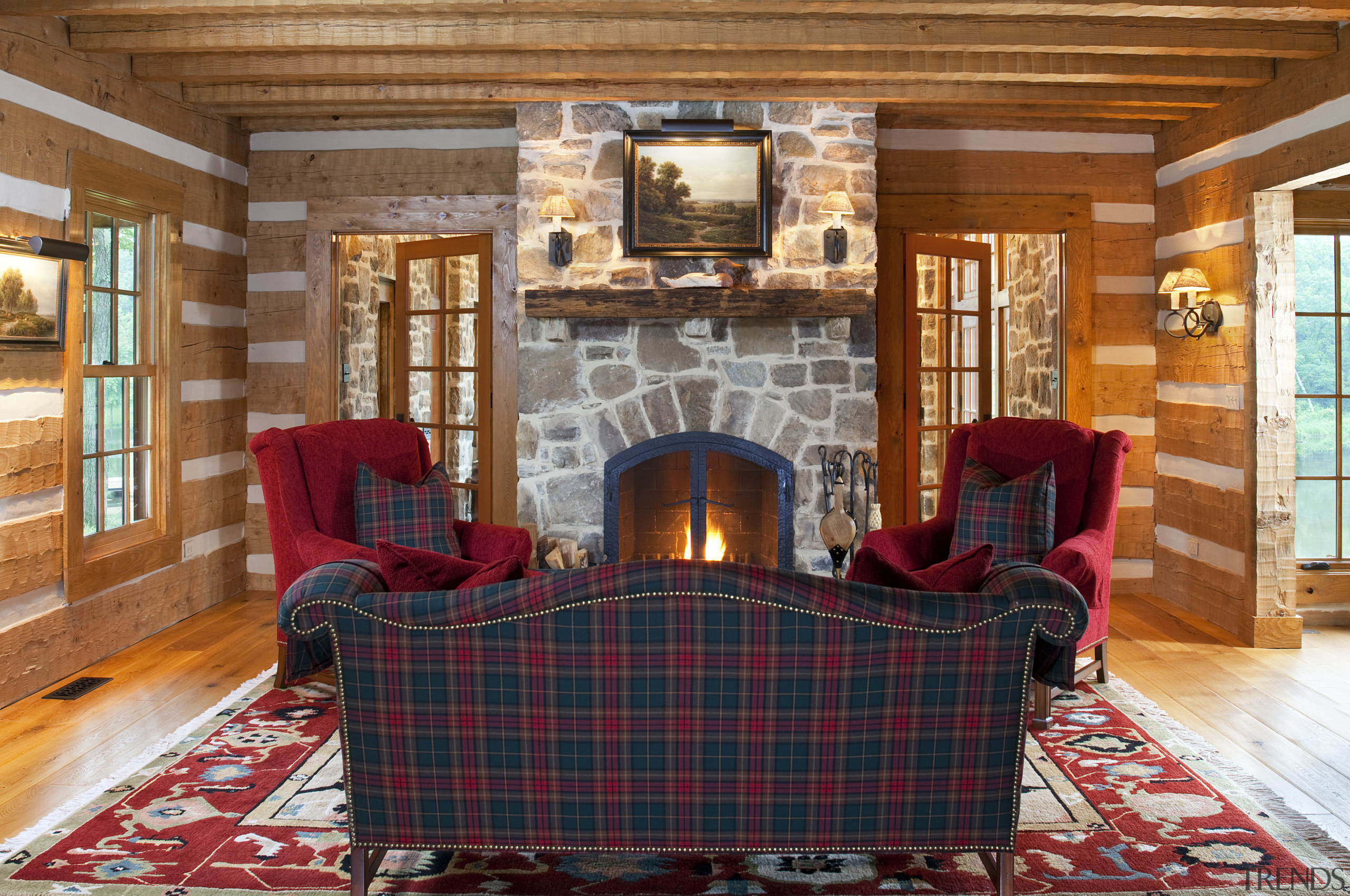 View of tartan couch in front of stone estate, fireplace, floor, flooring, hardwood, hearth, home, house, interior design, living room, real estate, room, wall, wood, wood flooring, brown