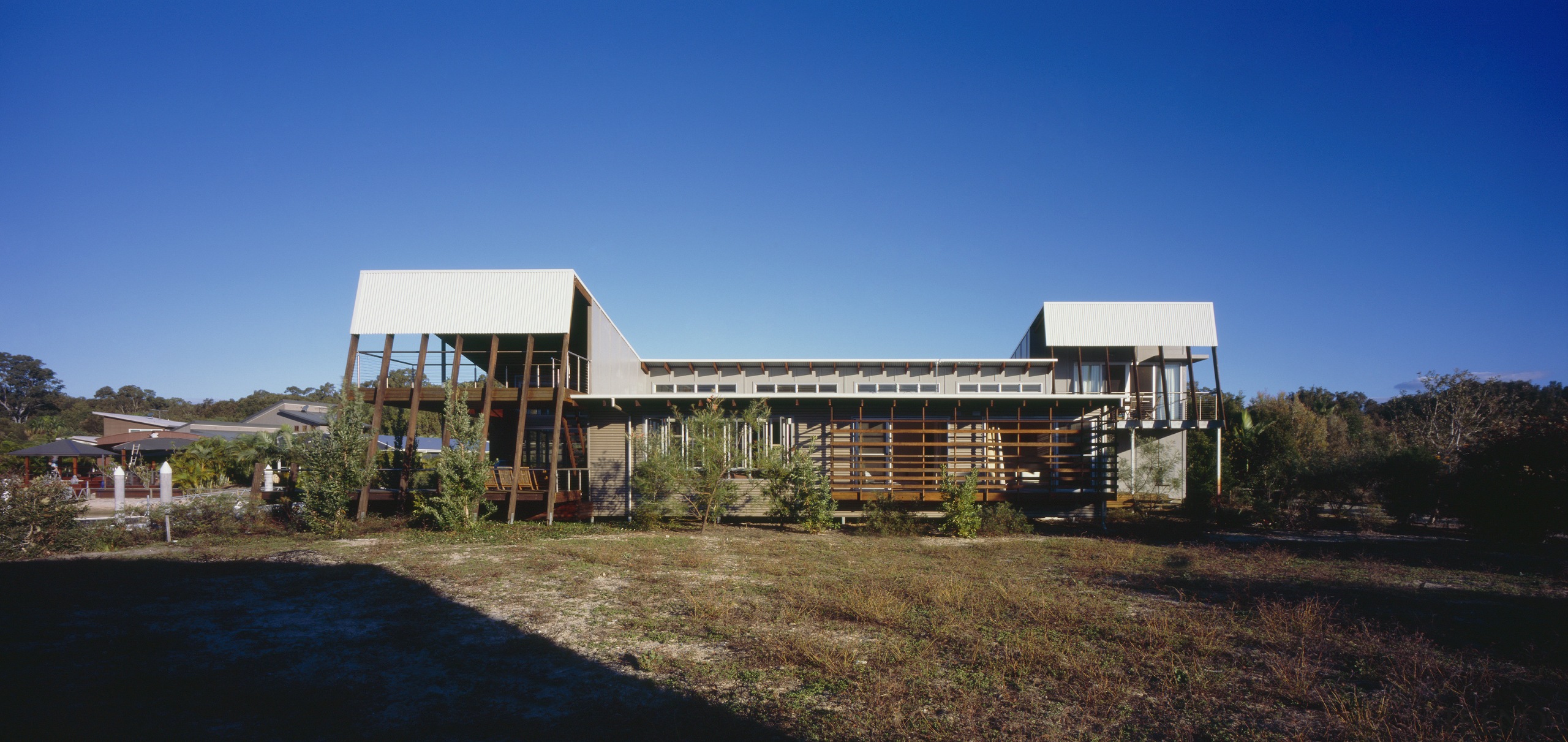 Exterior view of a canal-side beach house which architecture, building, corporate headquarters, estate, facade, home, house, property, real estate, residential area, sky, blue