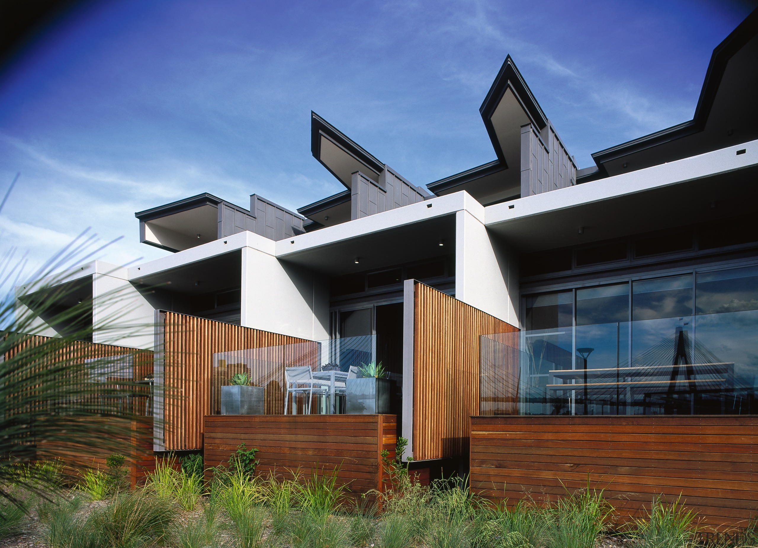 An exterior view of an apartment and patio architecture, building, cottage, estate, facade, home, house, property, real estate, residential area, roof, sky, blue, black