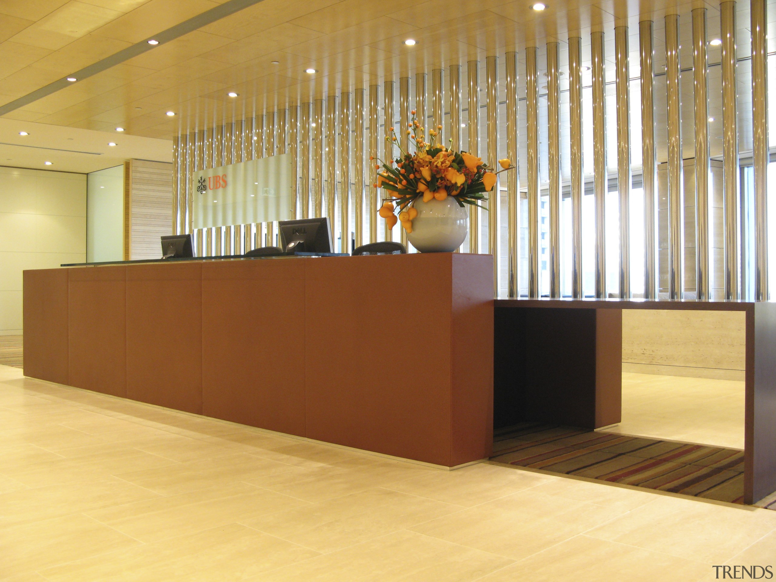 The leather and wenge veneer reception desk reflects floor, flooring, furniture, hardwood, interior design, lobby, wall, orange, brown