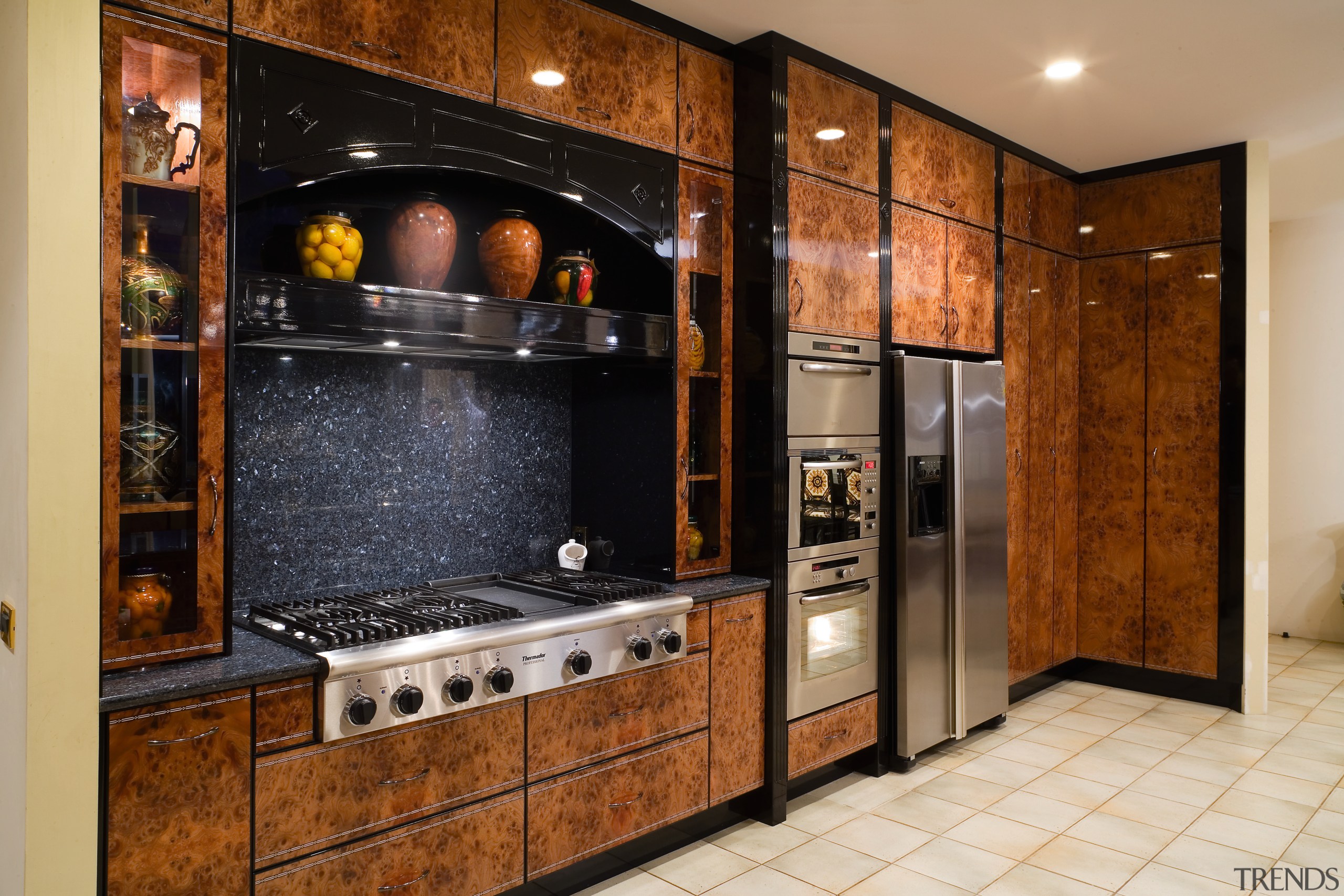 View of this kitchen featuring tiled flooring, lacquered cabinetry, countertop, flooring, home appliance, kitchen, room, brown, orange, black