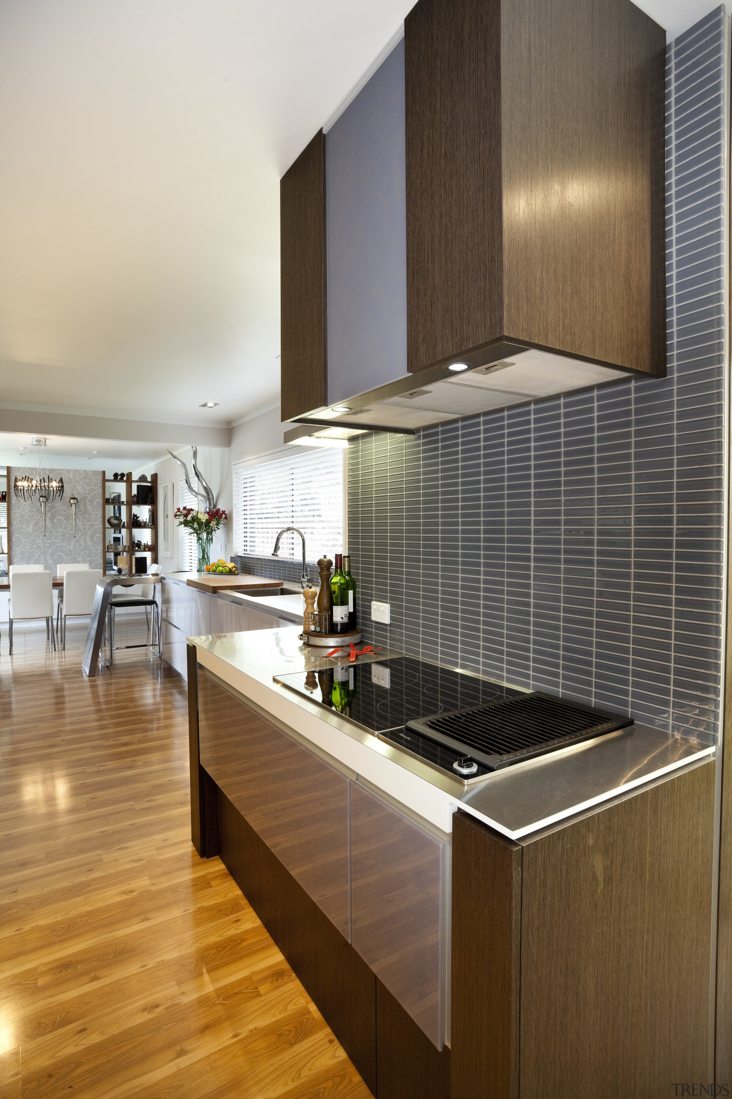 Glass cabinets beneath this cooktop are framed by cabinetry, countertop, cuisine classique, floor, flooring, hardwood, interior design, kitchen, room, brown, white