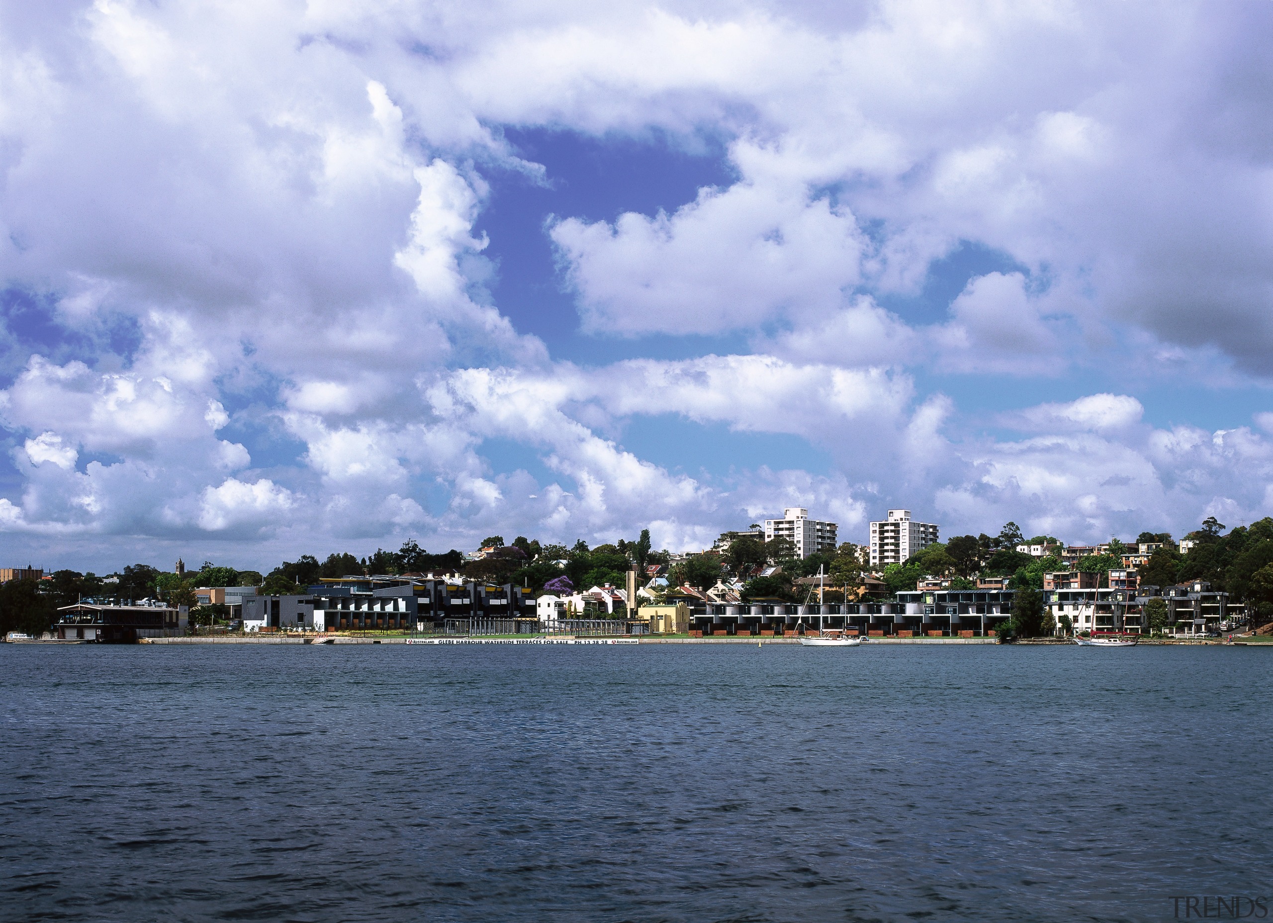 A view of the development from the water. bay, body of water, calm, city, cloud, coast, coastal and oceanic landforms, daytime, horizon, lake, loch, ocean, reservoir, river, sea, shore, sky, skyline, tree, water, waterway, teal